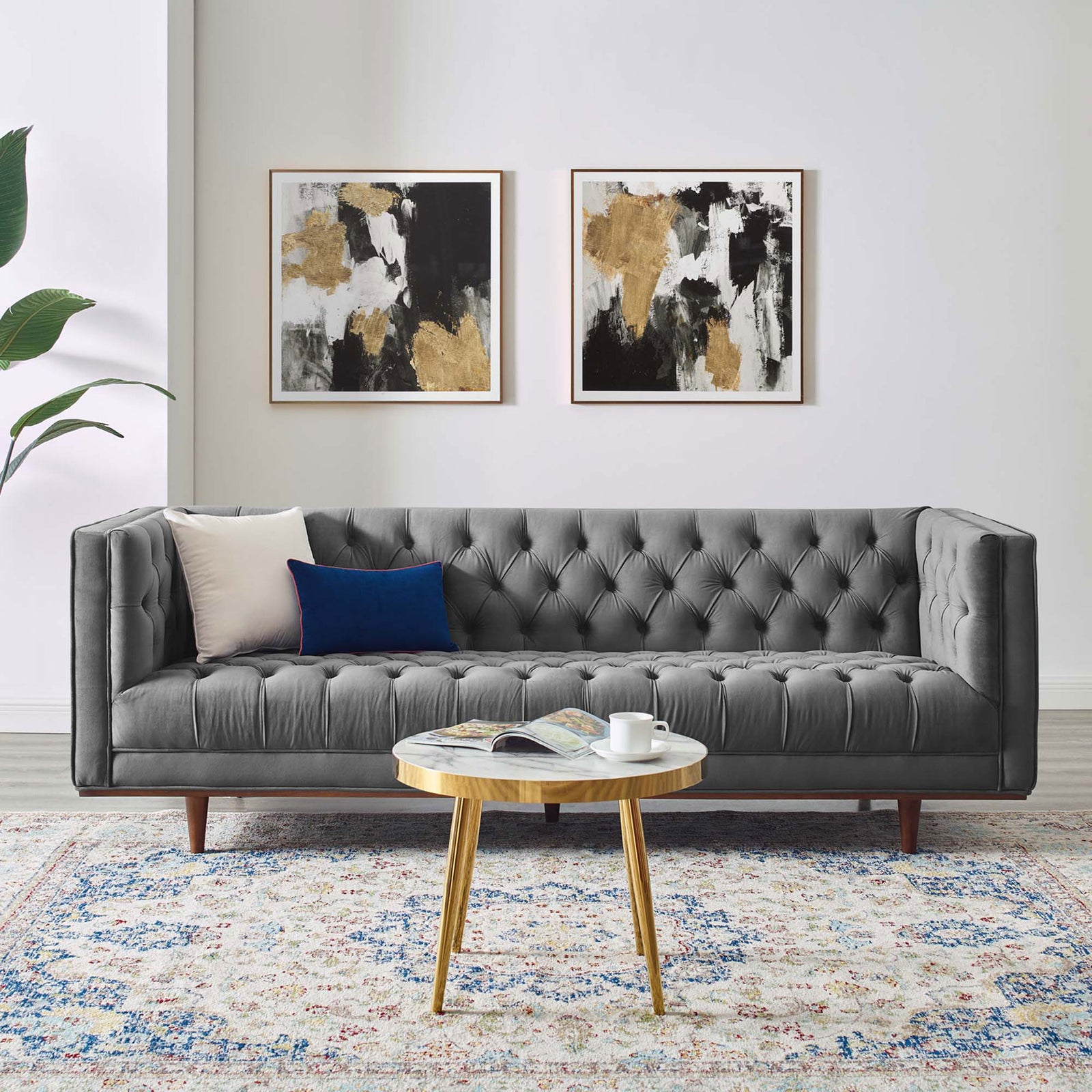 Gray velvet tufted sofa styled in a modern living room with art and round wood table || EEI-4722-GRY || front_angle_room