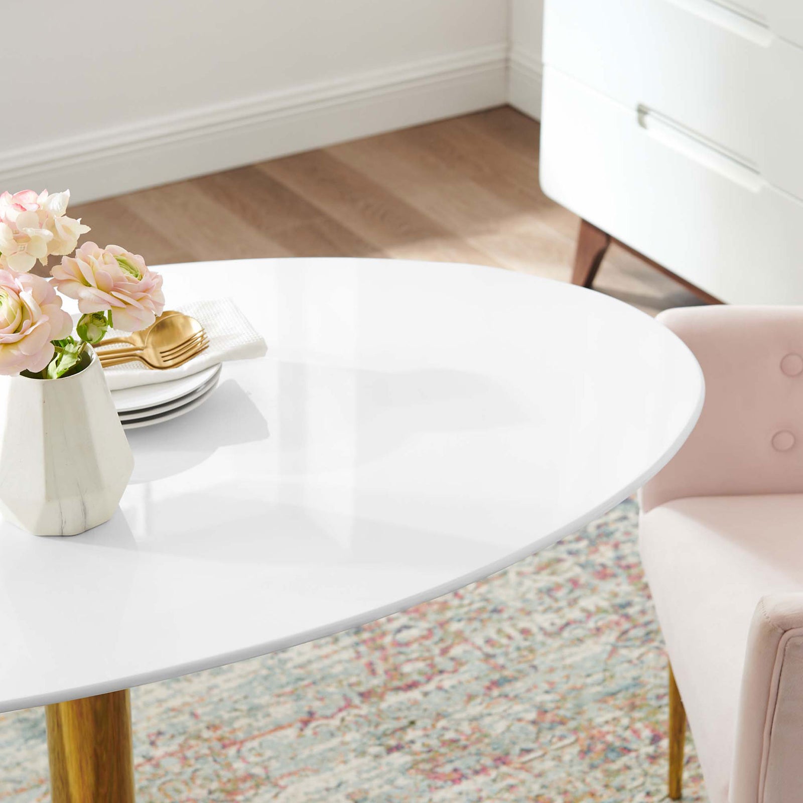 Close-up of Verne 48-inch oval tabletop with decor emphasizing the sleek white dining surface || EEI-4750-GLD-WHI || detail_room