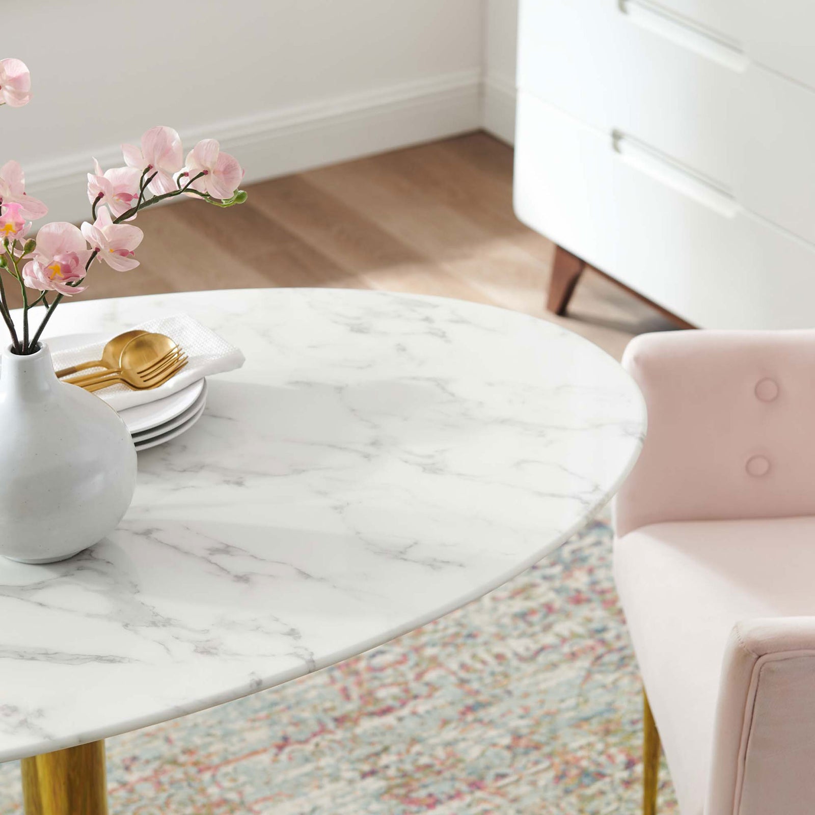 Oval marble-look tabletop set with vase and gold flatware by a blush chair || EEI-4752-GLD-WHI || detail_room