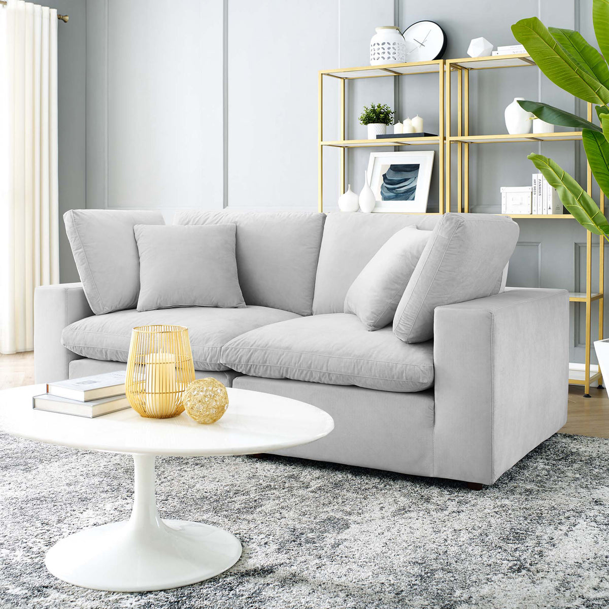 A light gray velvet loveseat brings plush two-seat comfort to a bright living space