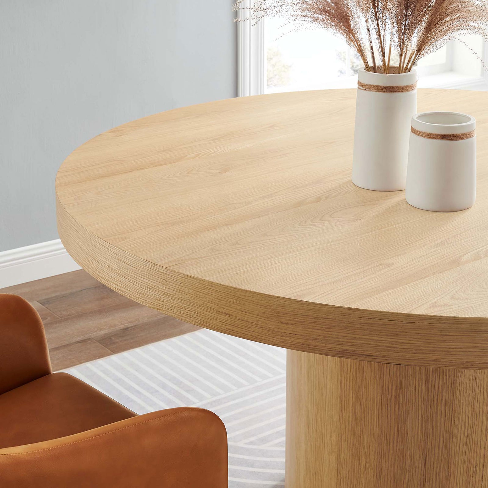Styled round oak table surface with neutral decor accents bringing warmth to a modern dining space || EEI-4911-OAK || detail_room