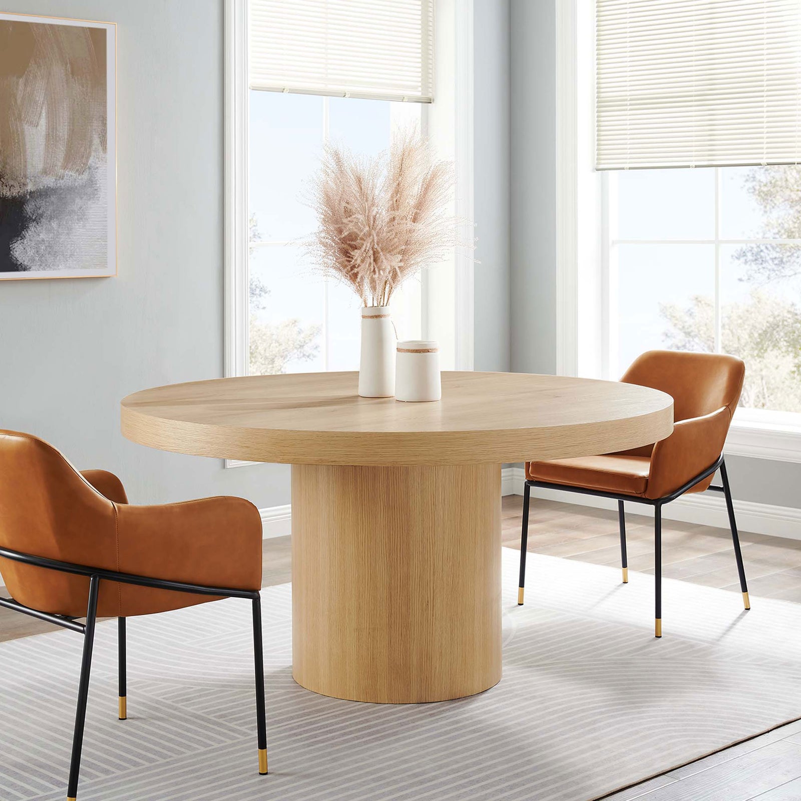 Round oak pedestal dining table styled with contemporary chairs in a bright, inviting dining room || EEI-4911-OAK || front_angle_room