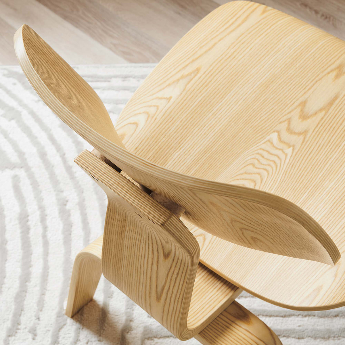 Layered plywood edges frame the flowing wood grain of the curved backrest