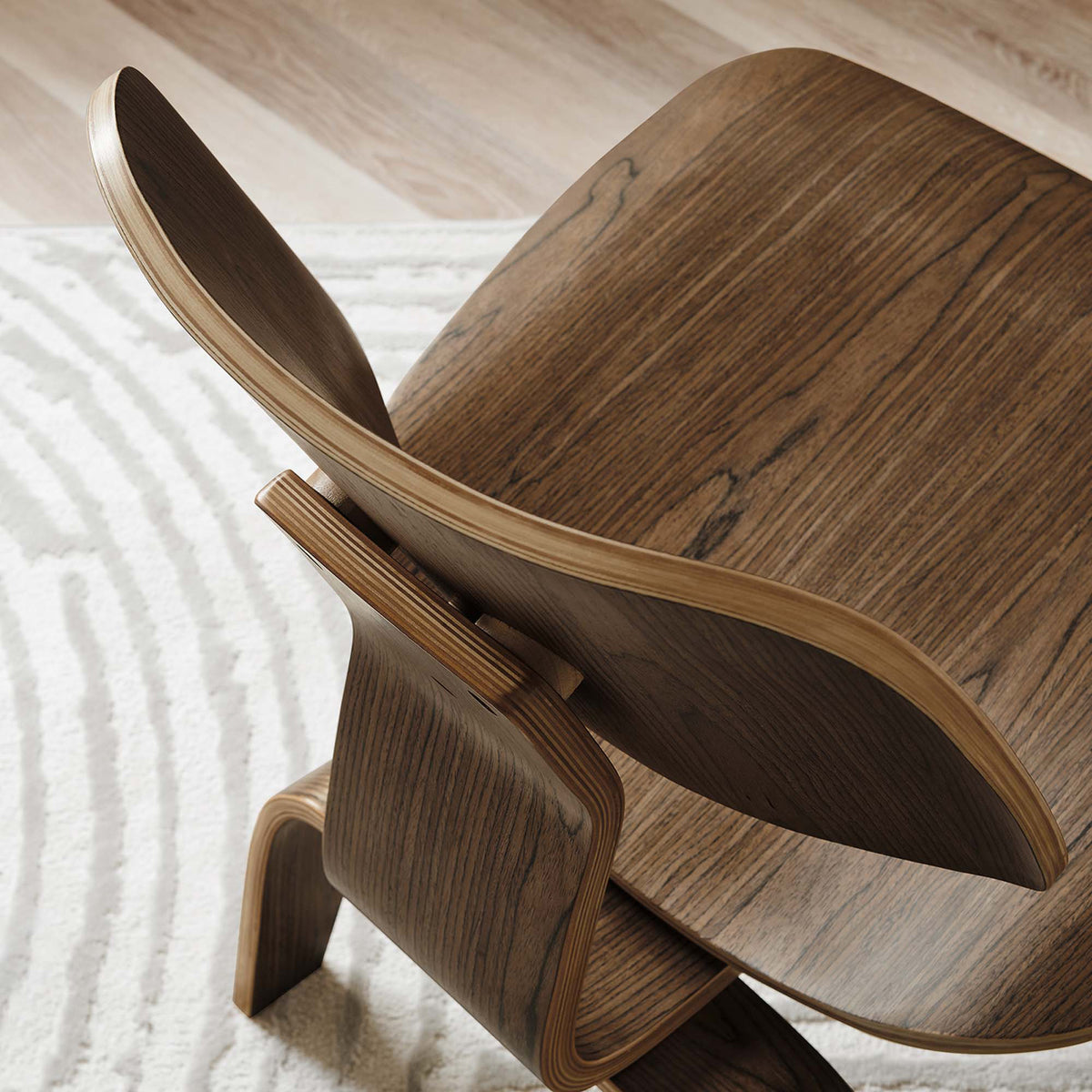 Dark wood grain and exposed plywood layers emphasize the curved backrest