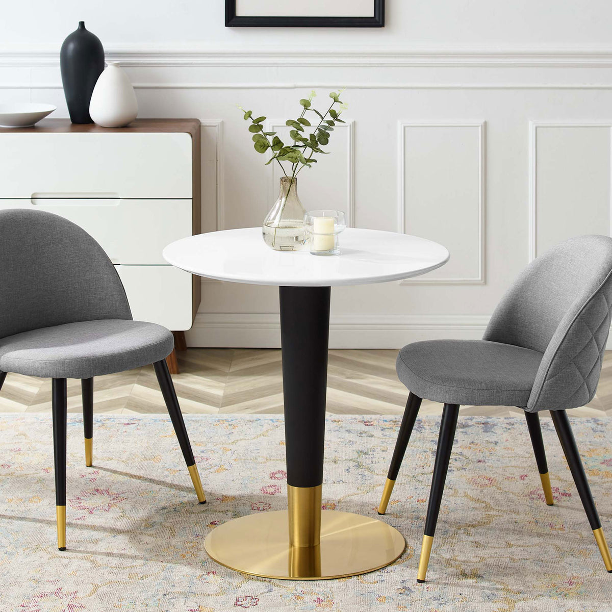 Round white 28 inch pedestal table styled with gray chairs in a bright dining room || EEI-5116-GLD-WHI || front_angle_room