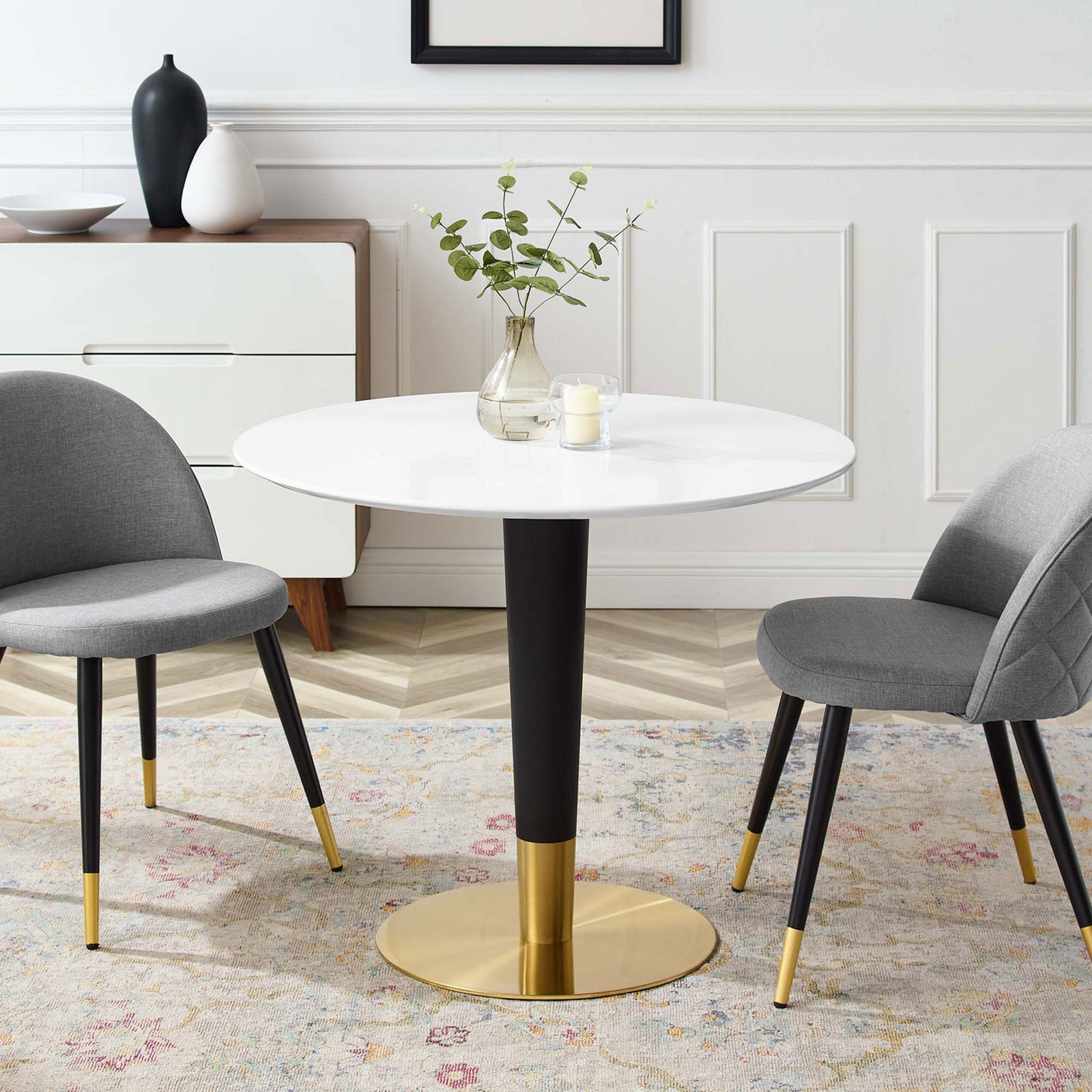 Round white 36 inch pedestal table arranged with decor and gray chairs in a chic dining room || EEI-5117-GLD-WHI || front_angle_room