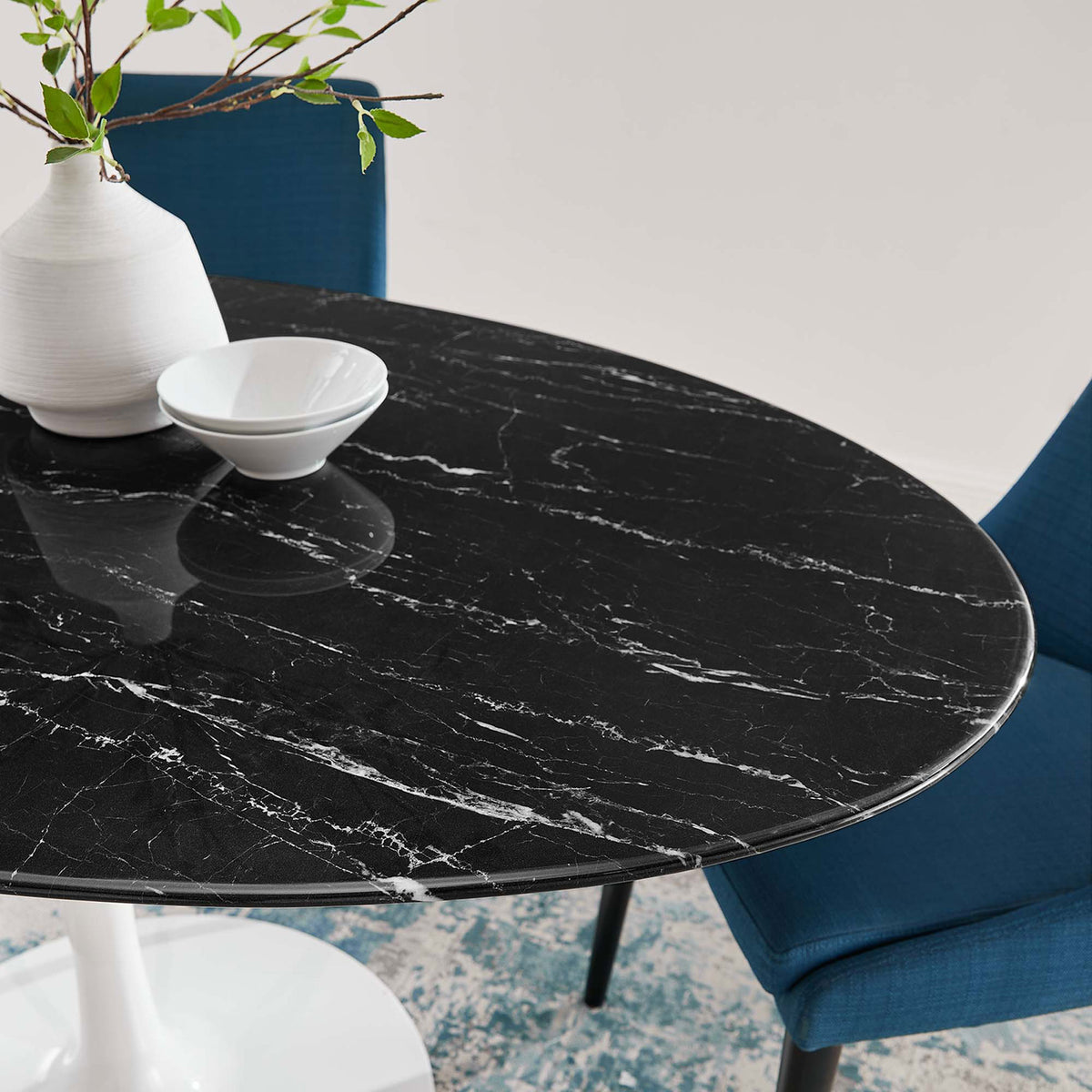 Black faux marble tabletop of the Lippa 60 in. dining table paired with modern blue chairs and white decor || EEI-5186-WHI-BLK || detail_room