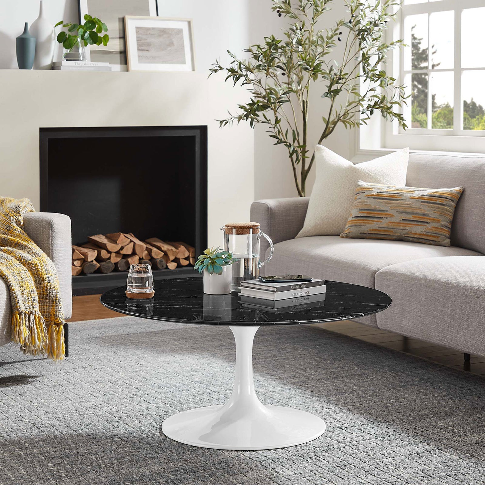 Modern round coffee table anchors a cozy living room with its white pedestal and dark top || EEI-5191-WHI-BLK || front_angle_room