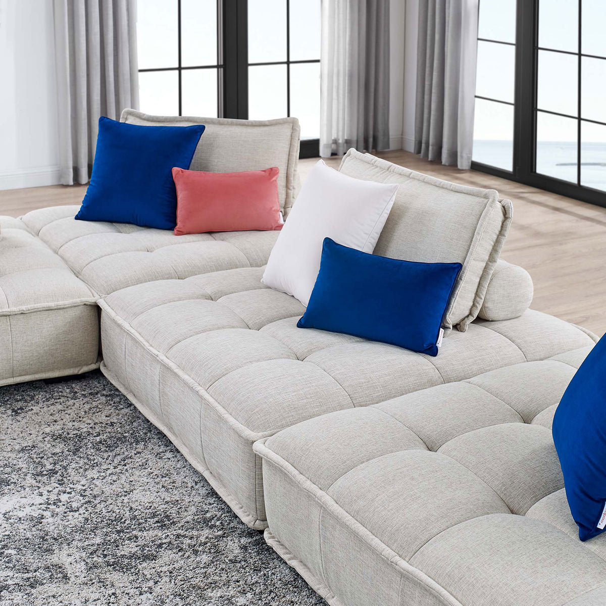 Low-profile beige sectional stretches along the living room, complemented by vibrant accent pillows and rug || EEI-5208-BEI || detail_room