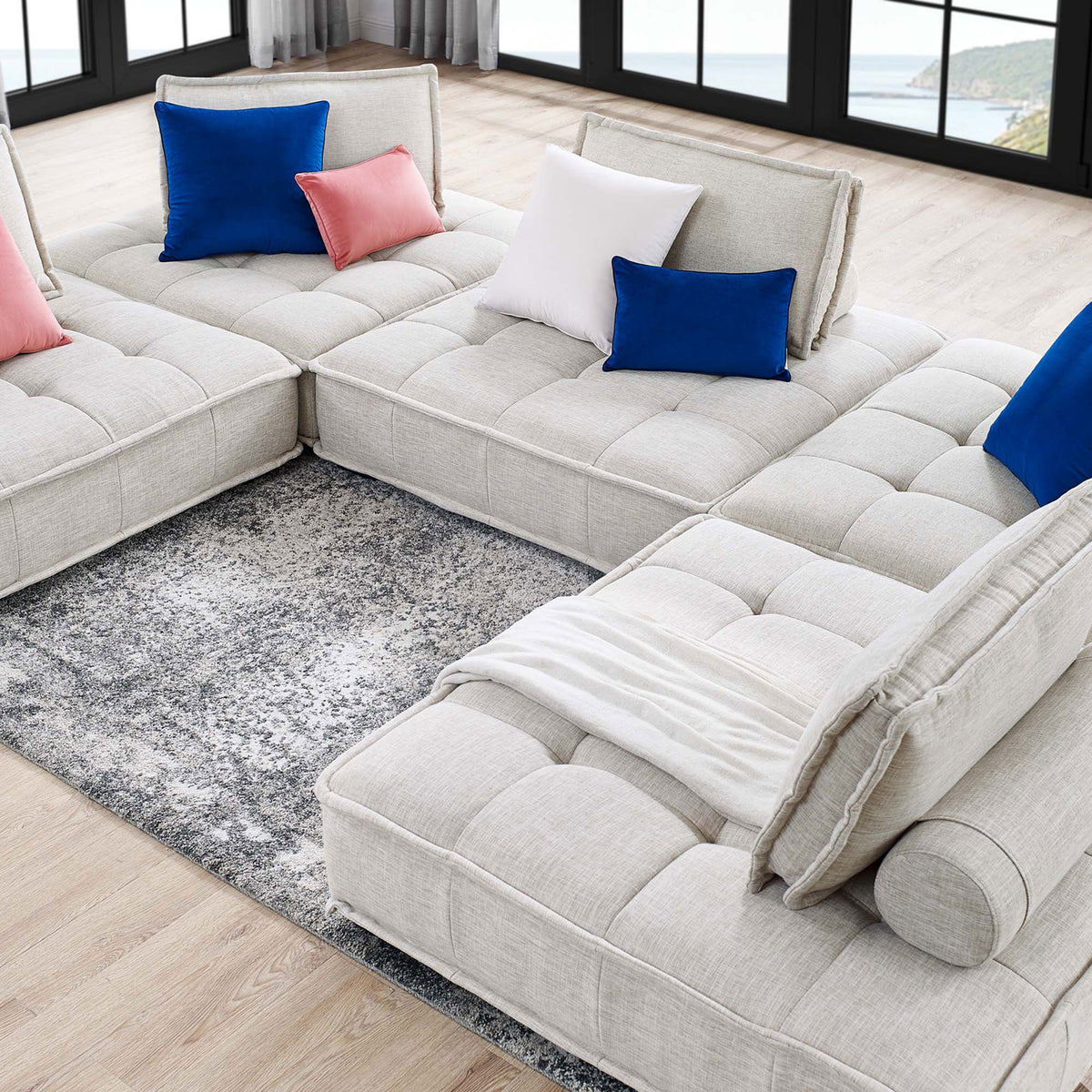 Spacious beige modular sectional arranged around a rug with accent pillows for open, casual gathering spaces || EEI-5210-BEI || top_angle_room