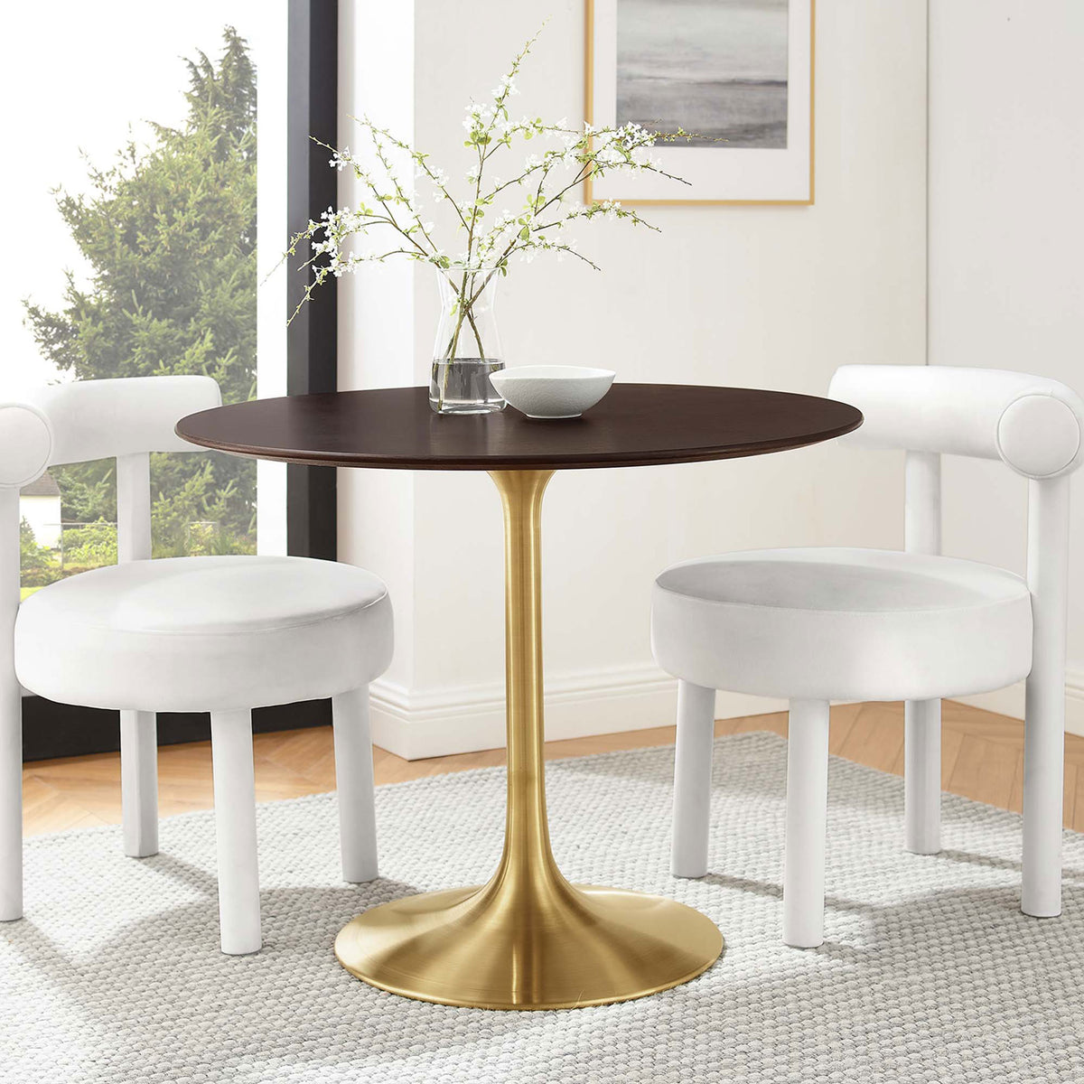 Round cherry walnut pedestal table with brushed gold base paired with two white chairs in bright room || EEI-5214-GLD-CHE || front_angle_room