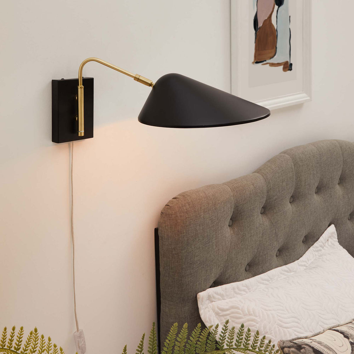 Illuminated swing arm sconce casts warm light across the headboard and bedside table. || EEI-5296-BLK || front_angle_on_room