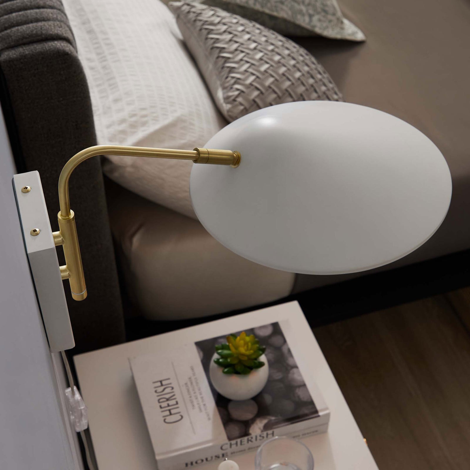 White Journey sconce hovers above a styled bedside vignette with books and greenery. || EEI-5296-WHI || top_angle_room