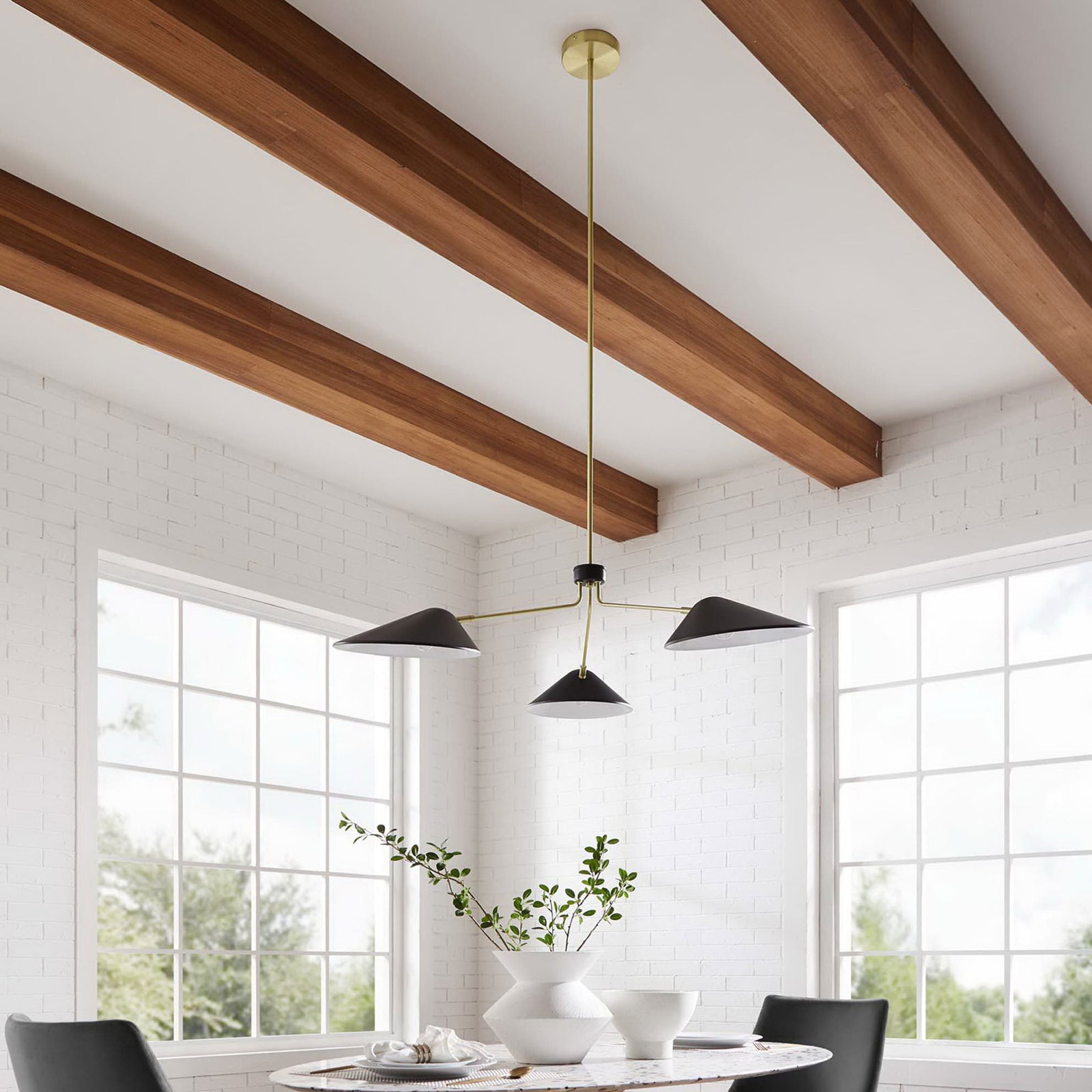 Striking black-and-brass pendant brings a sculptural focal point above a dining table in a bright room || EEI-5297-BLK || front_angle_room