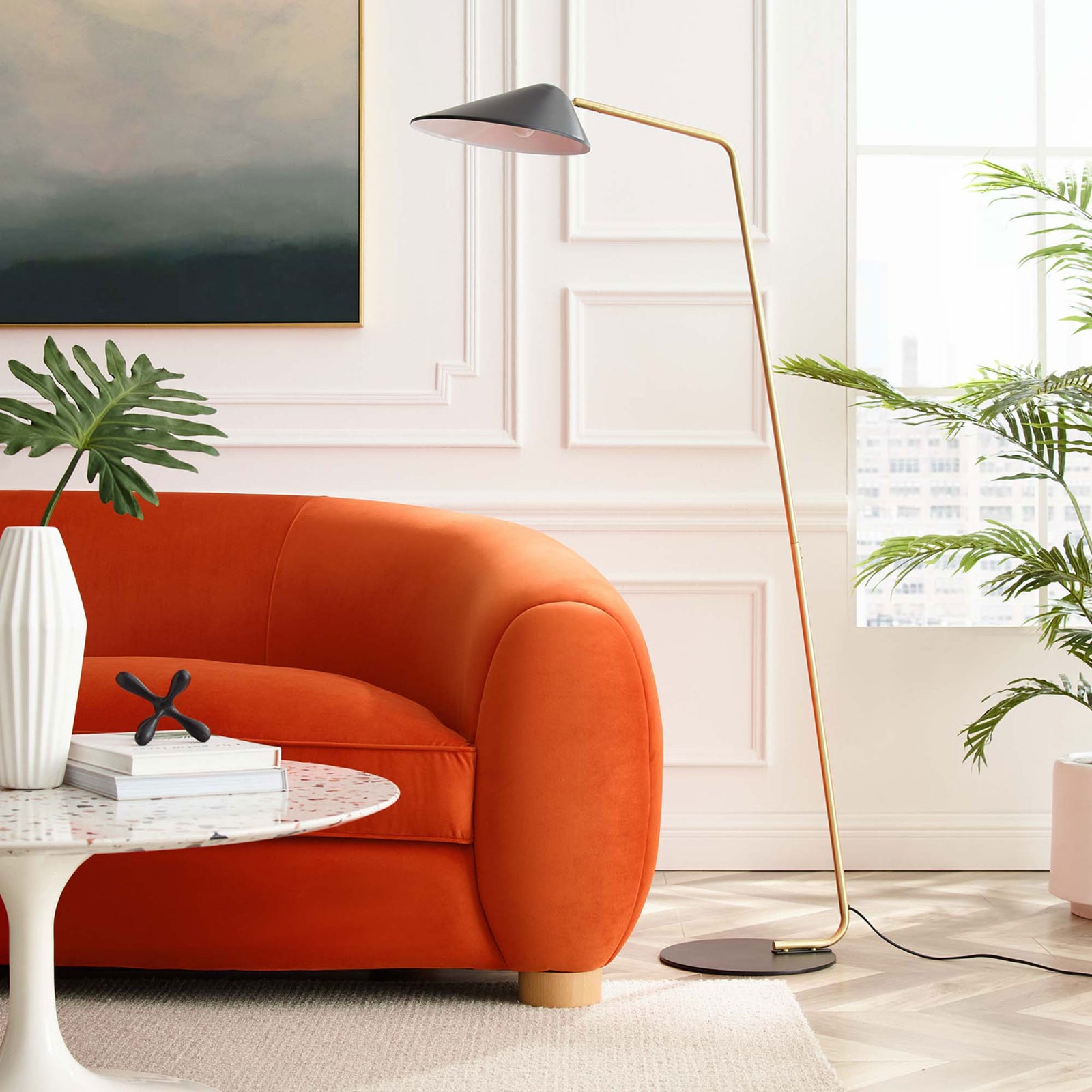 Black and brass floor lamp adds modern accent lighting beside an orange sofa in a bright living room || EEI-5298-BLK || front_angle_room