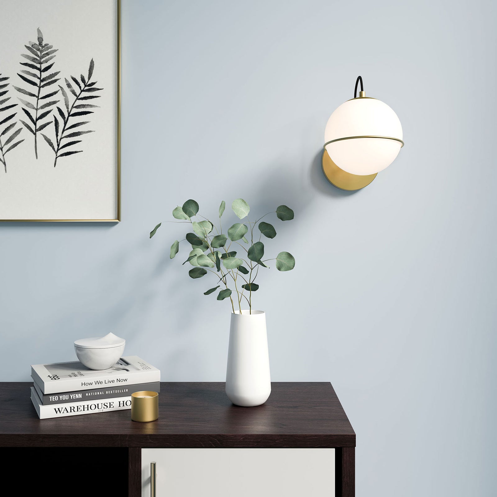 Warmly glowing opal globe wall sconce in satin brass illuminating a console vignette with greenery || EEI-5308-OPA-GLD || front_on_room