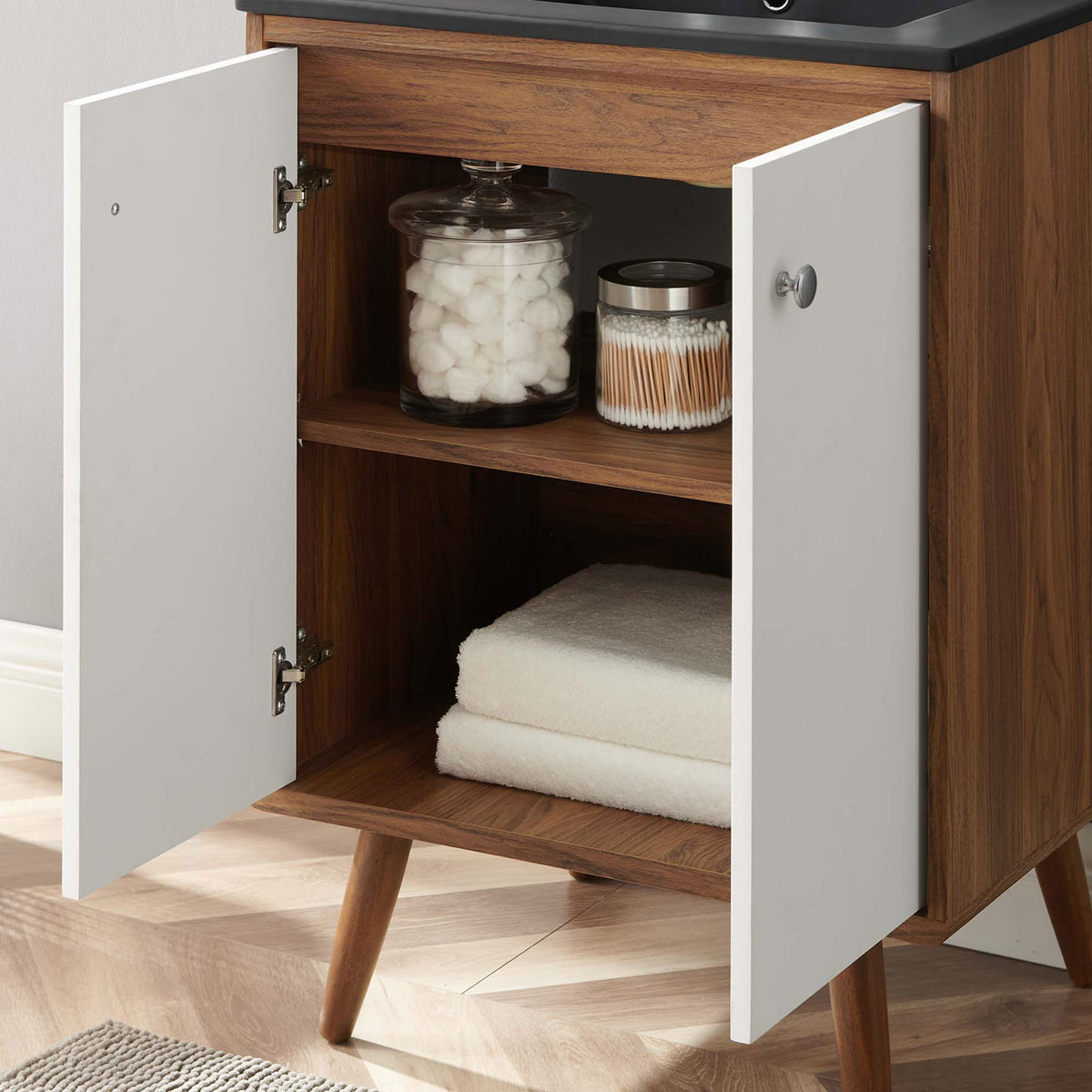 Open cabinet reveals neatly organized towels and jars inside a wood-grain interior || EEI-5363-WHI-BLK || storage_open_room