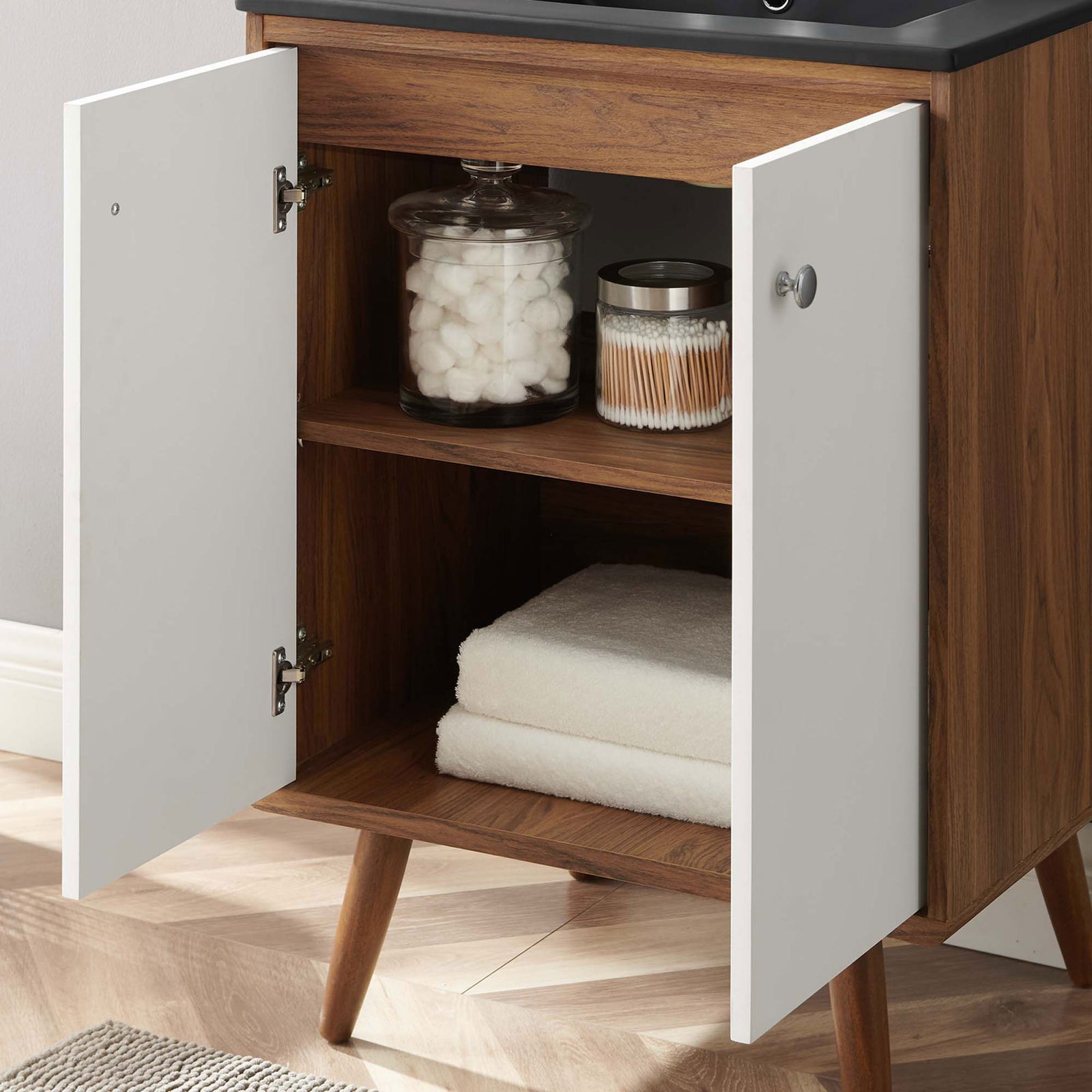 Open cabinet reveals neatly organized towels and jars inside a wood-grain interior || EEI-5363-WHI-BLK || storage_open_room