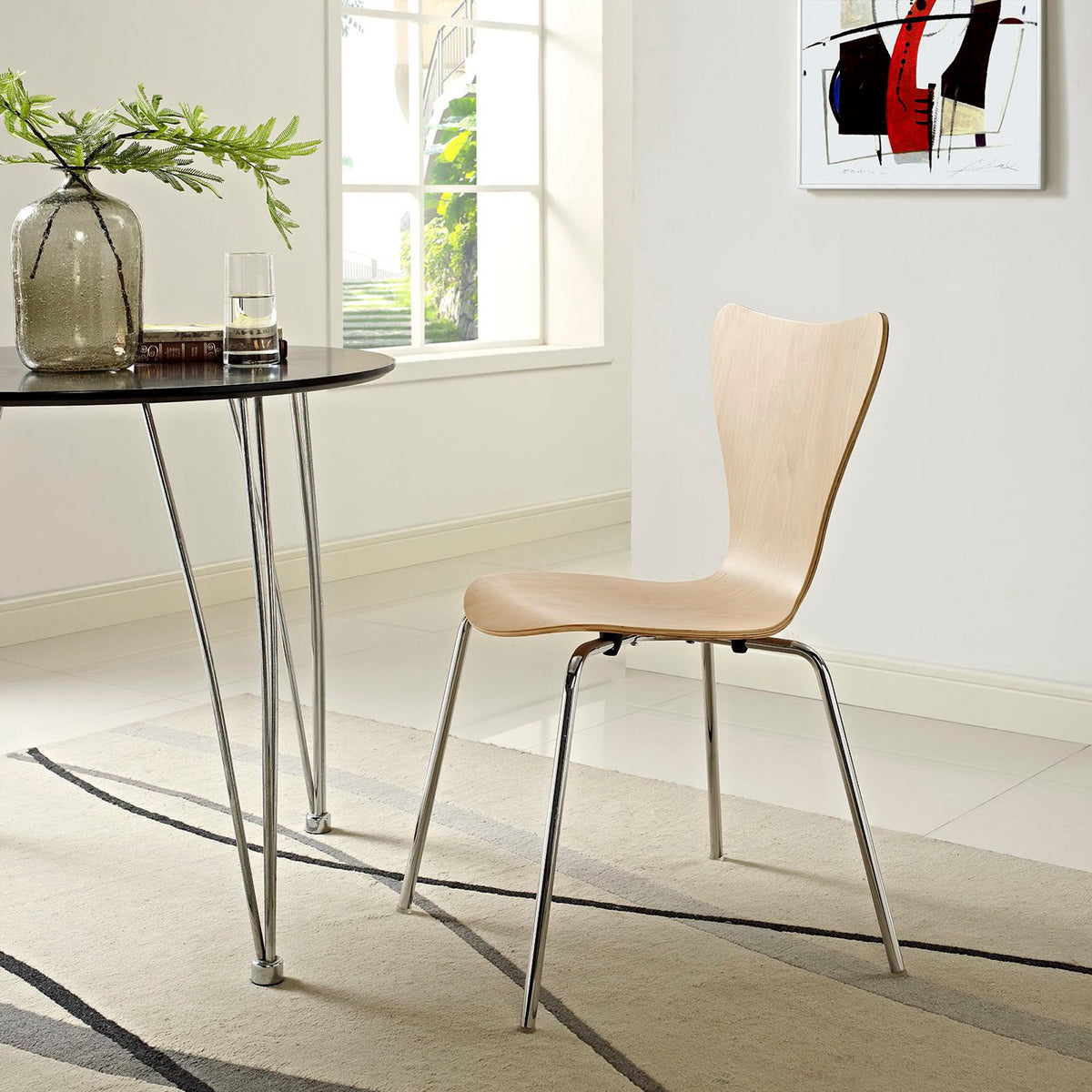 A natural-finish chair brings gentle curves and sleek chrome legs to a bright dining nook.