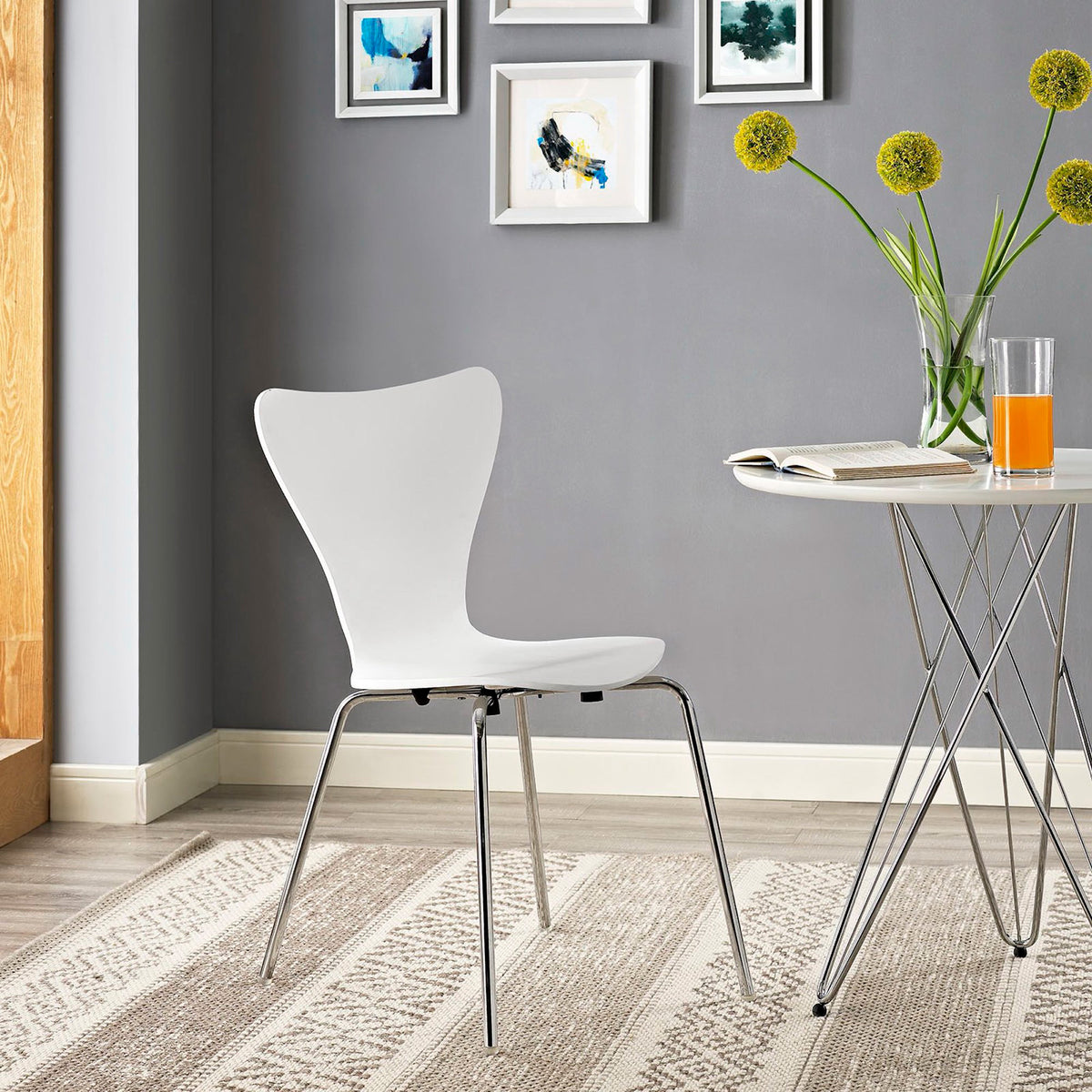 A white sculpted chair pairs a sweeping backrest with chrome legs in a cozy dining nook.