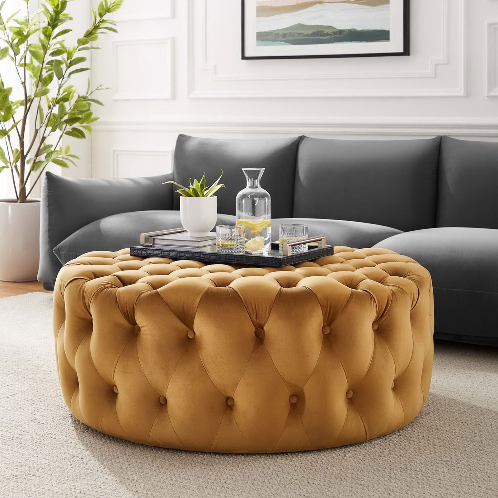 Large round cognac velvet ottoman anchoring a modern living room with inviting tufted comfort || EEI-5469-COG || front_angle_room