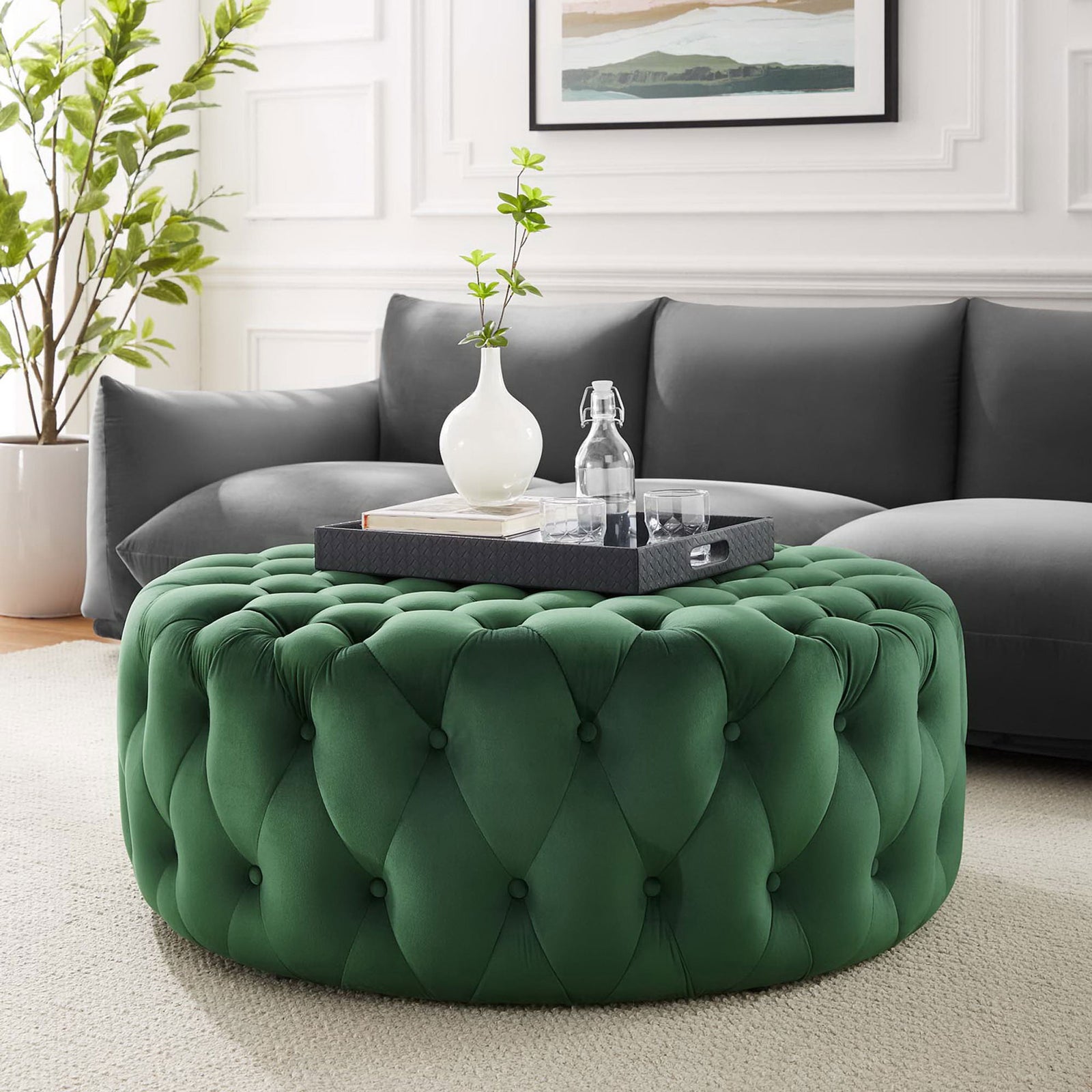 Emerald velvet ottoman styled in a modern living room as a plush centerpiece coffee table || EEI-5469-EME || front_angle_room