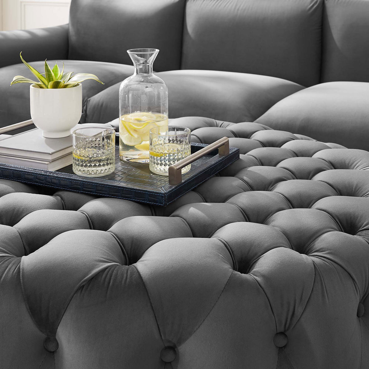 Tufted gray velvet ottoman topped with a tray, drinks, and decor, adding soft texture and function to the living room || EEI-5469-GRY || detail_room