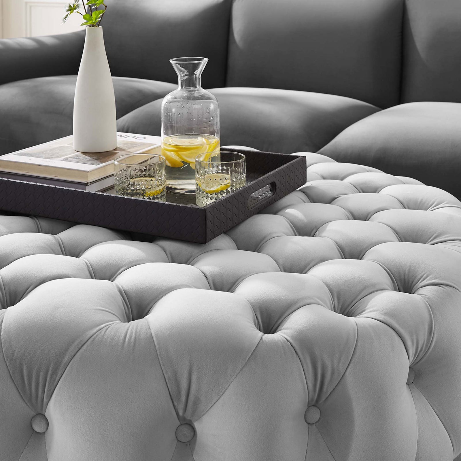 Tufted velvet ottoman styled with a tray, drinks, and decor to highlight its soft light gray cushioned surface || EEI-5469-LGR || detail_room