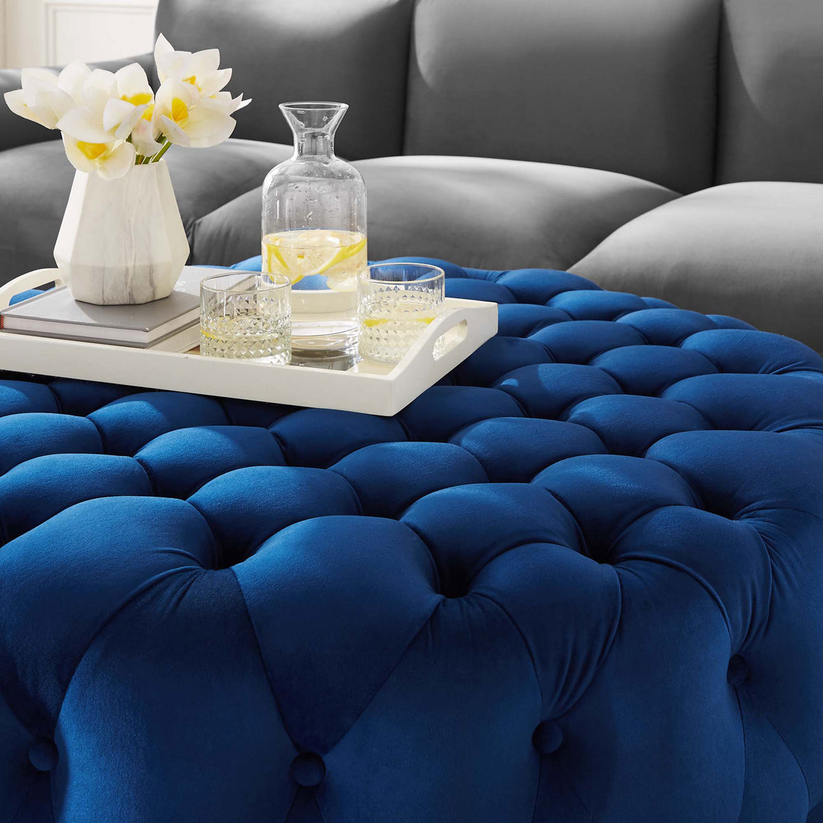 Button tufting and soft velvet upholstery create a cozy spot for serving drinks on this navy round ottoman || EEI-5469-NAV || detail_room