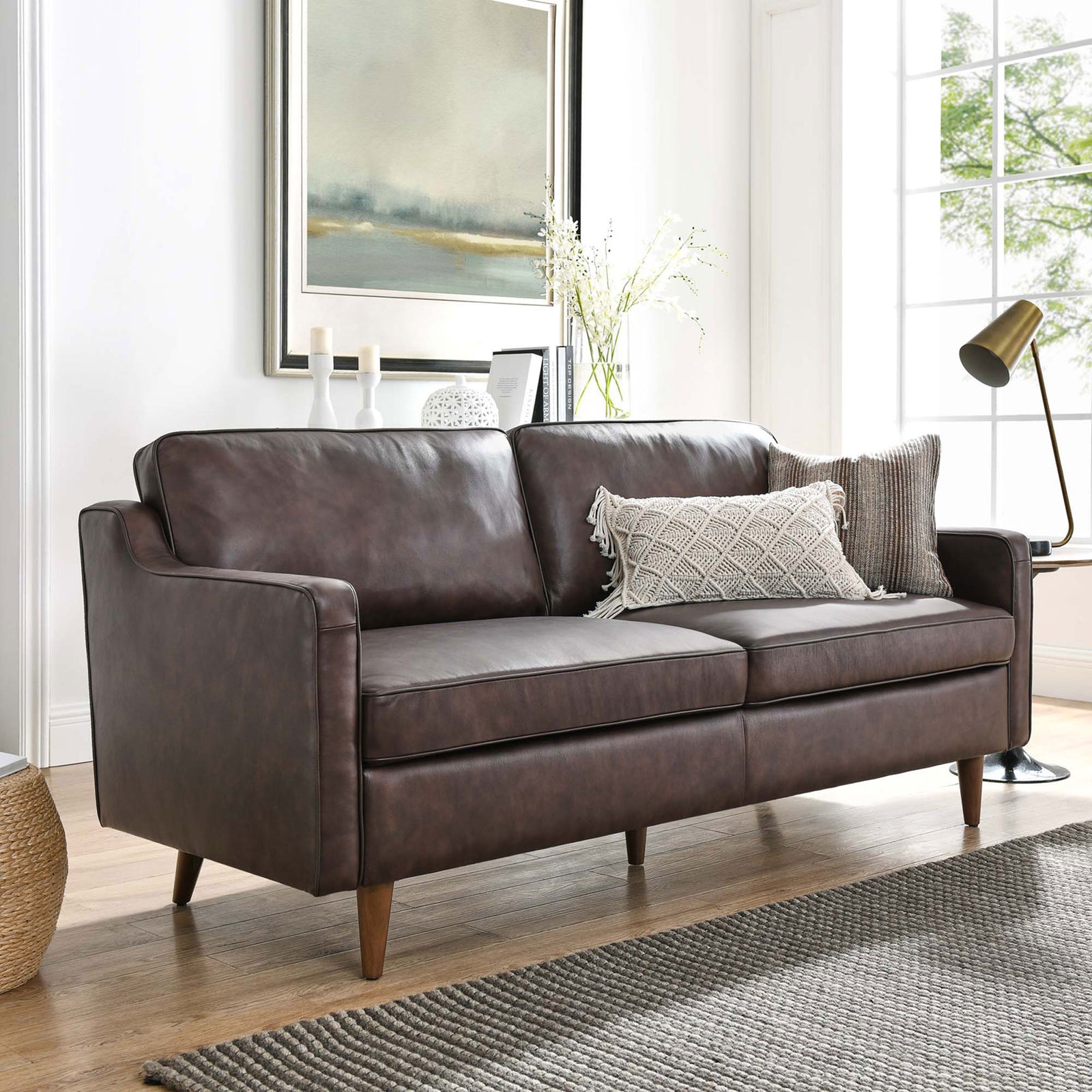 Impart brown leather sofa in a modern living room featuring slender arms, plush cushions, and tapered wood legs || EEI-5553-BRN || front_angle_room