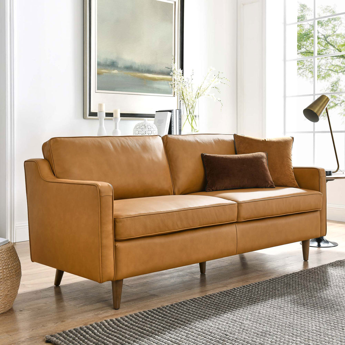 Tan leather sofa styled in a bright living room with accent pillows, rug, and modern decor || EEI-5553-TAN || front_angle_room