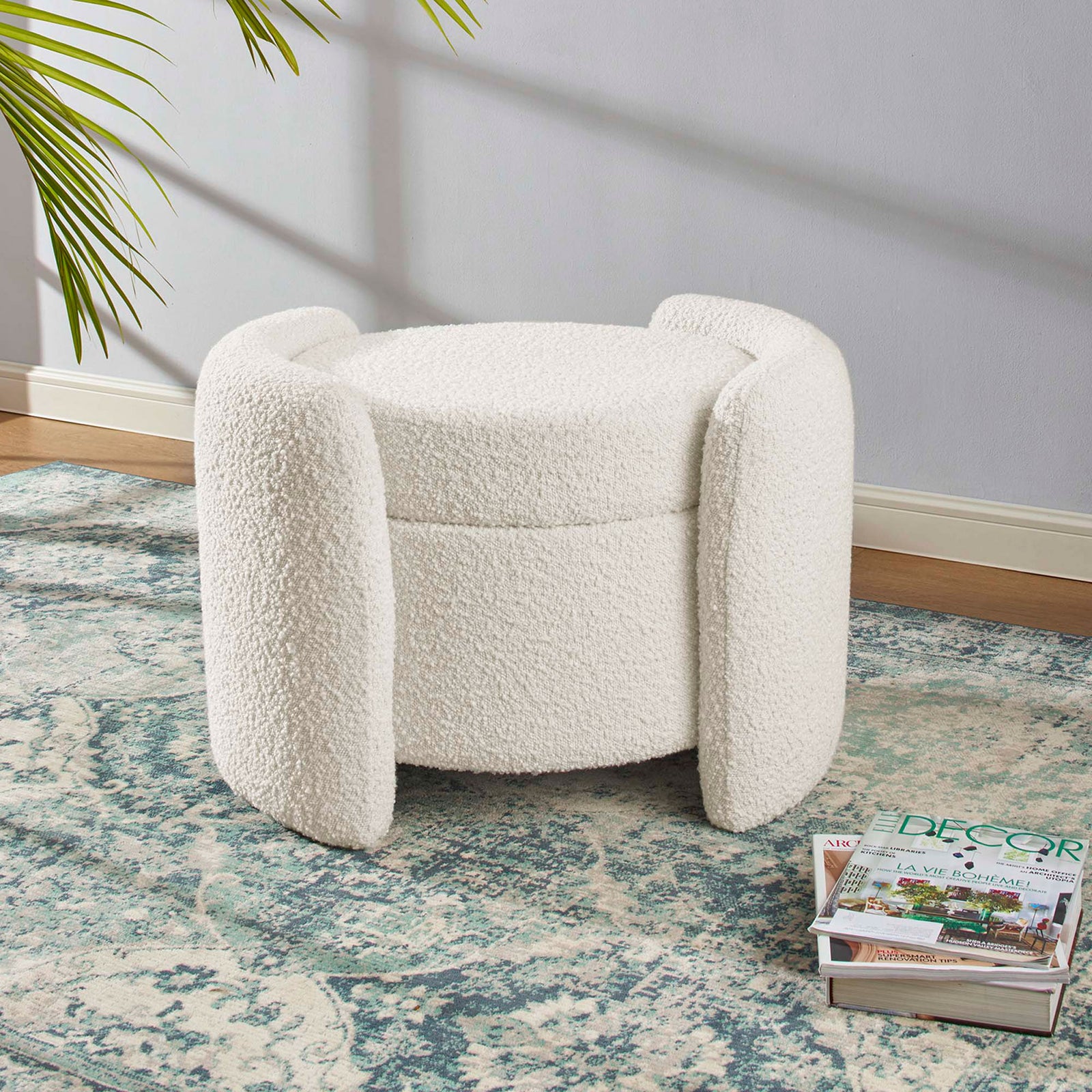 Ivory boucle storage ottoman styled on a patterned rug beside magazines in a bright living room || EEI-5561-IVO || front_room