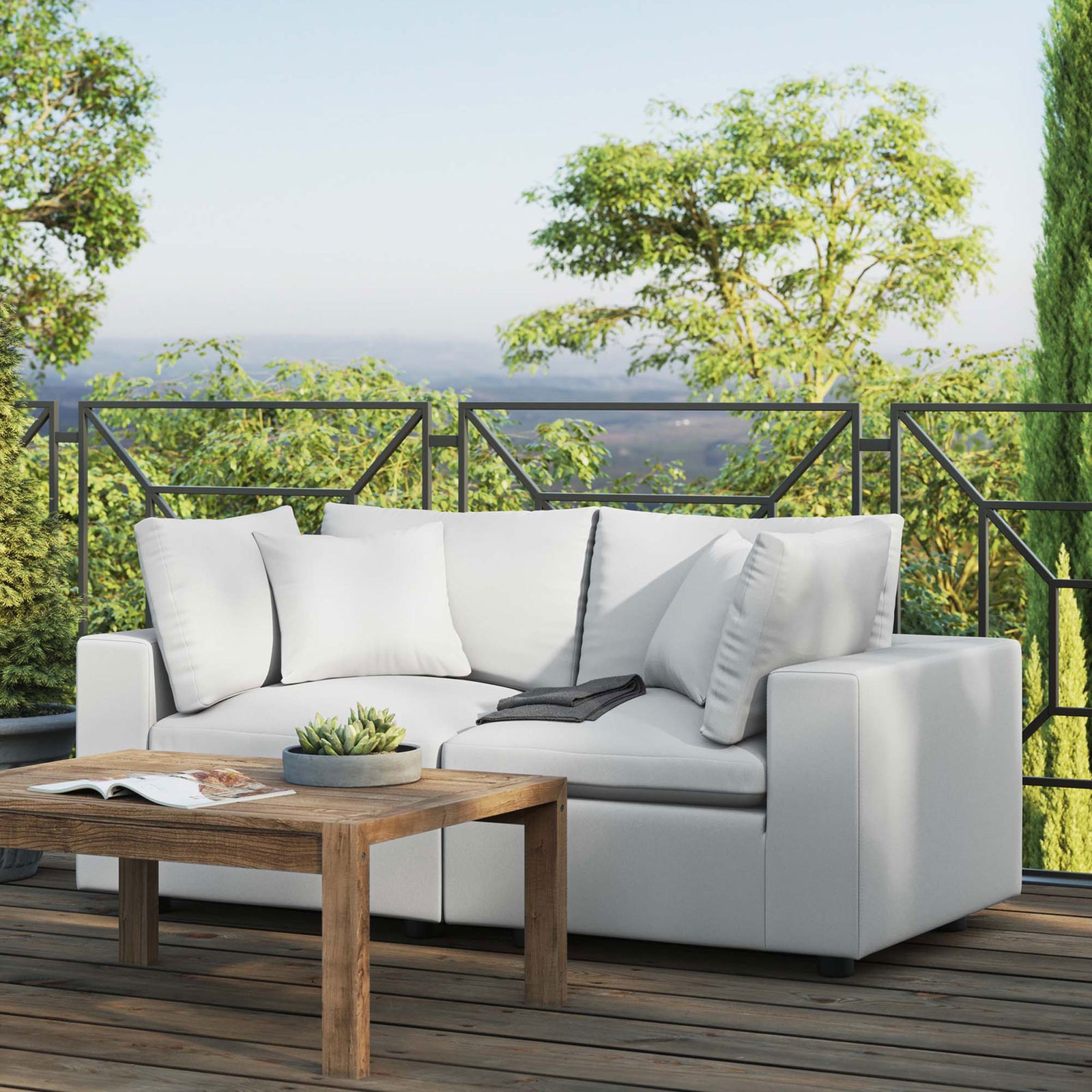 White outdoor loveseat on a sunlit deck framed by greenery and a rustic coffee table || EEI-5576-WHI || front_angle_room