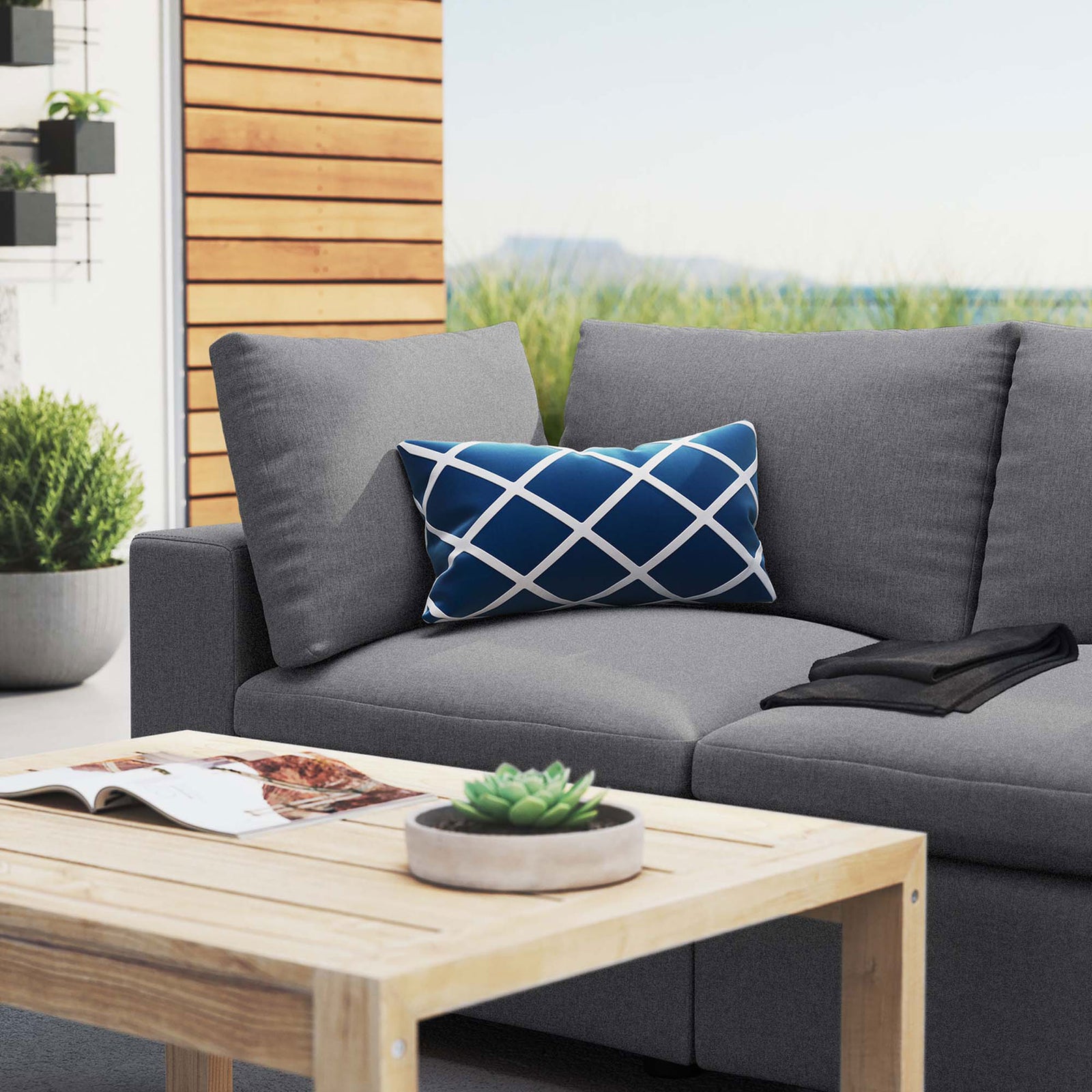 Gray patio loveseat styled with a light wood coffee table and blue accent pillow on a breezy terrace || EEI-5577-SLA || detail_room