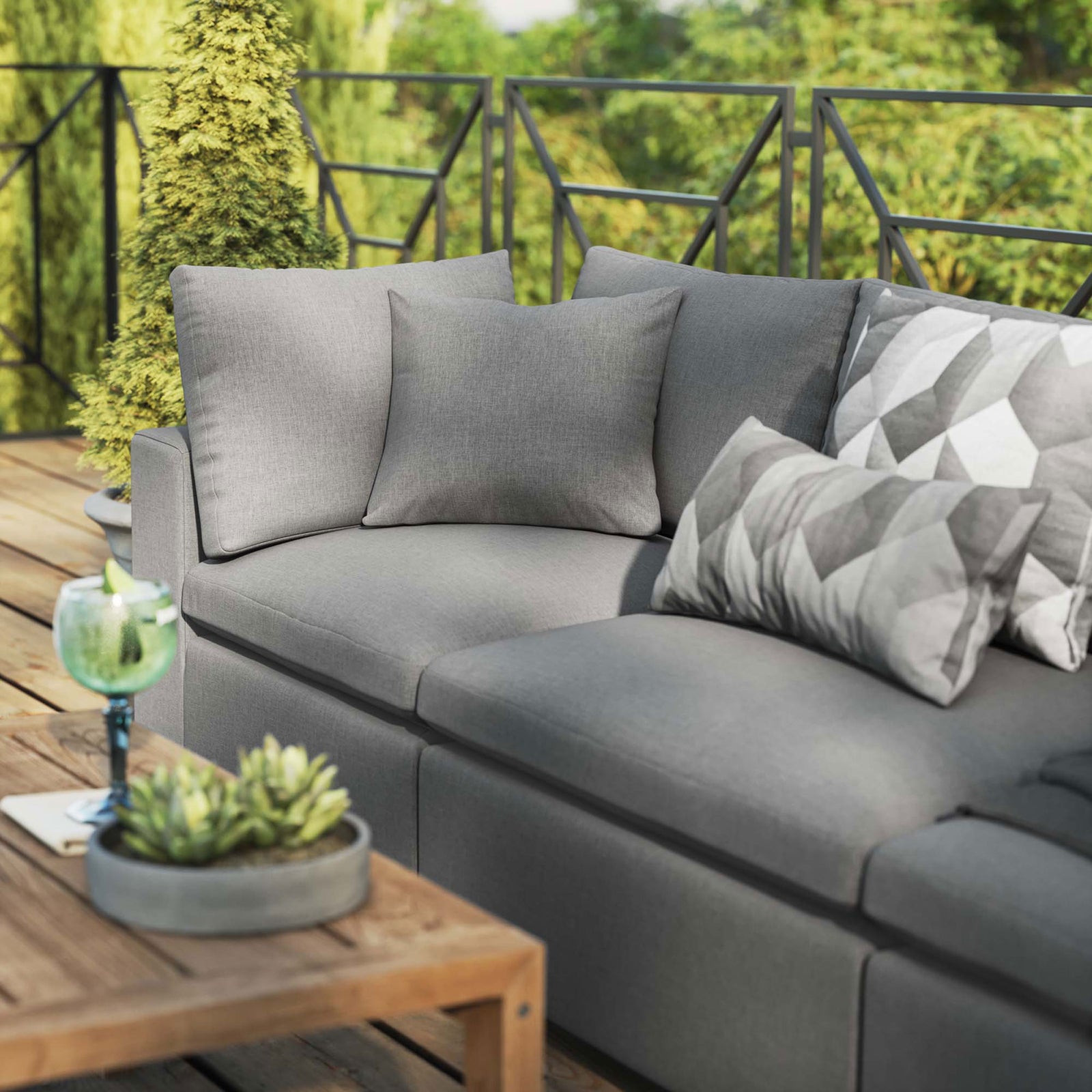 Charcoal outdoor sofa styled with accent pillows, greenery, and a wood coffee table on a sunny deck || EEI-5578-CHA || detail_room