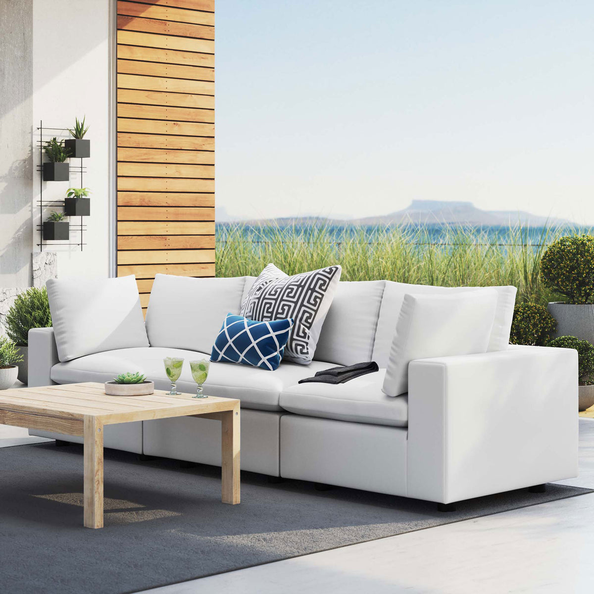 White Sunbrella three-seat outdoor sofa on a modern patio paired with a light wood coffee table || EEI-5579-WHI || front_angle_room