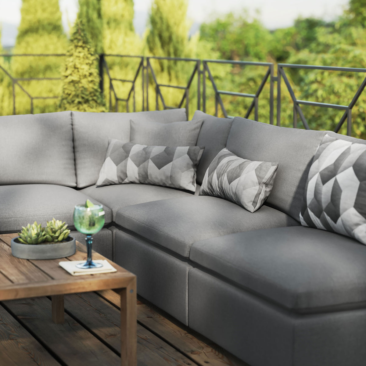 Charcoal outdoor sectional styled with patterned pillows and decor on a warm wood deck. || EEI-5587-CHA || detail_room