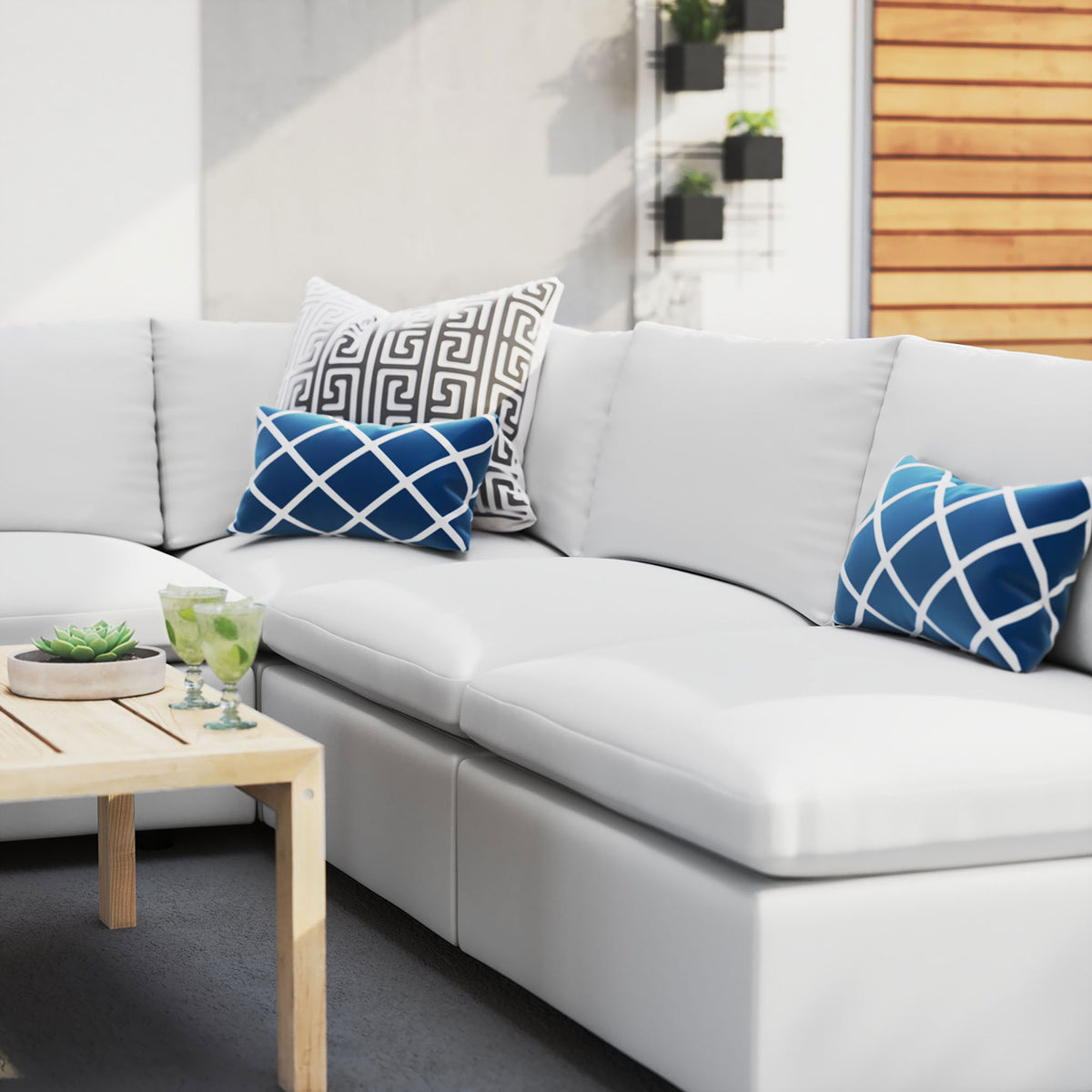 White Sunbrella outdoor sectional styled with graphic blue pillows on a bright, modern patio. || EEI-5588-WHI || detail_room