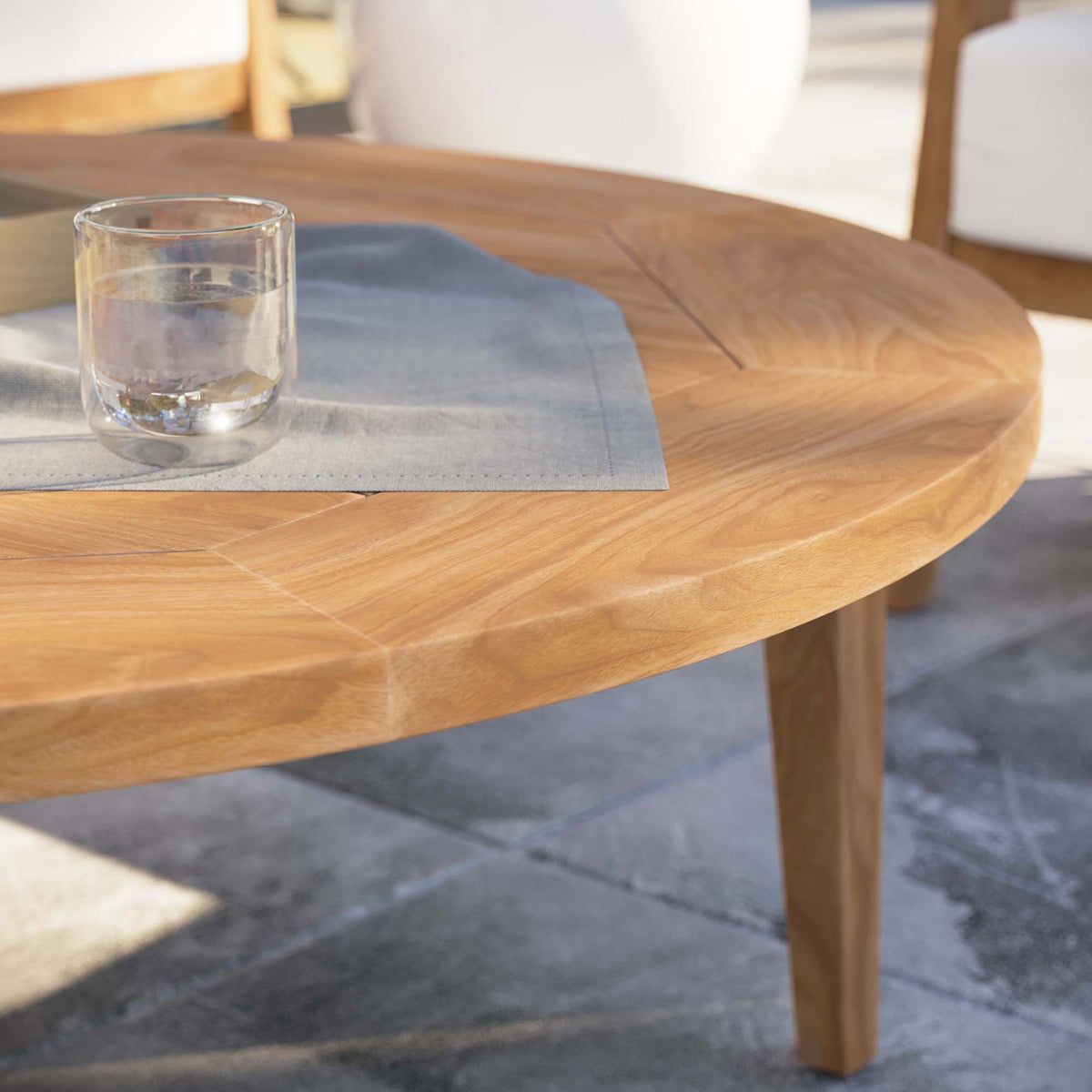 Natural teak coffee table styled with glassware on a modern stone patio || EEI-5603-NAT || detail_room