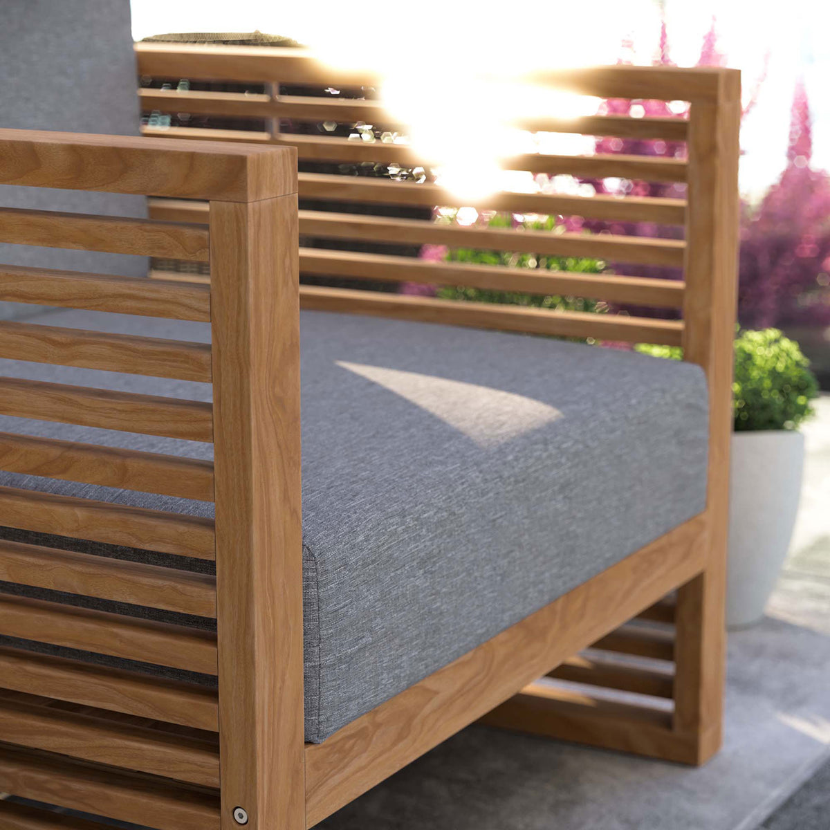 Teak armrest and gray cushion of the Carlsbad armchair catching warm patio sunlight. || EEI-5606-NAT-GRY || detail_room