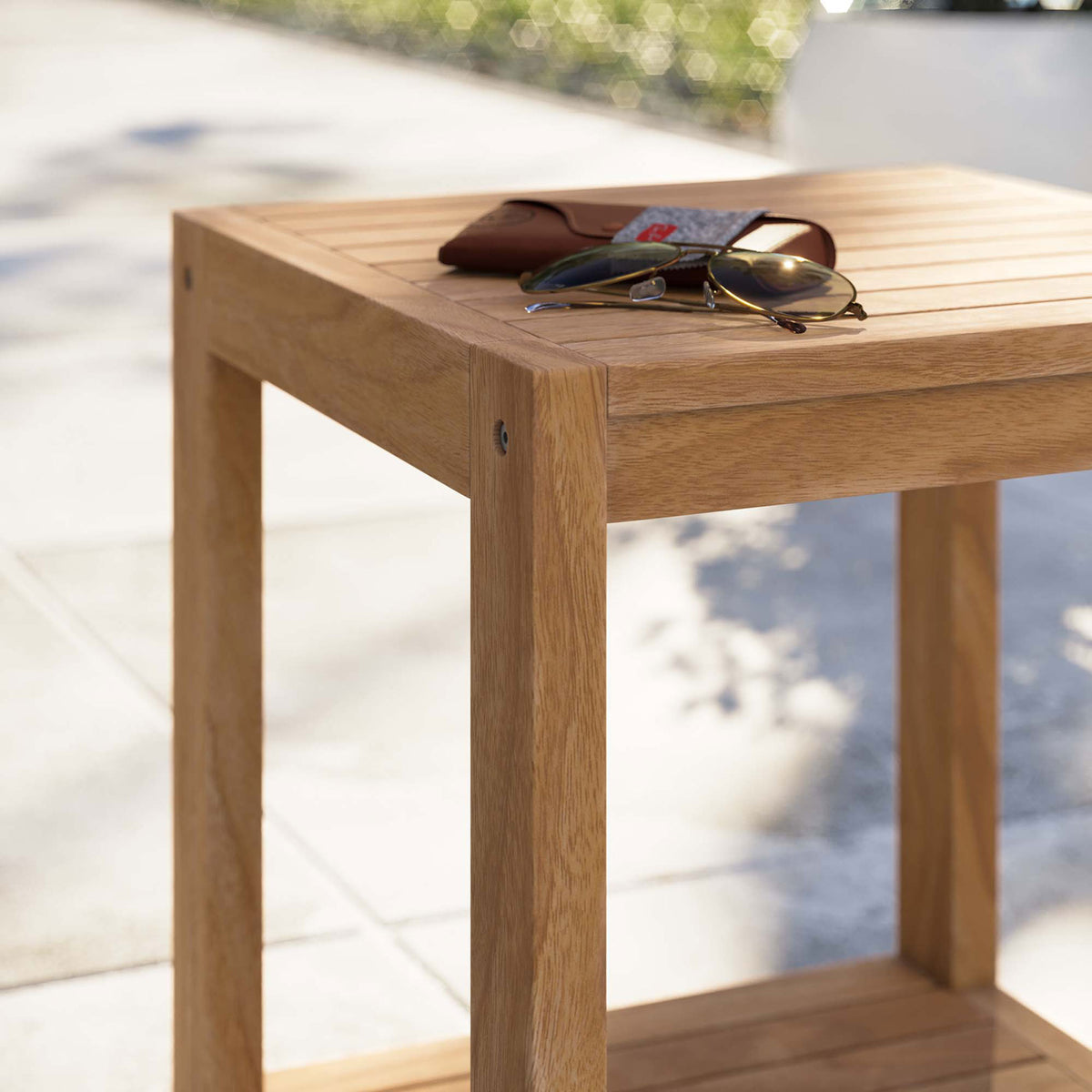 Teak outdoor side table styled with sunglasses on a sunny patio walkway || EEI-5607-NAT || detail_room