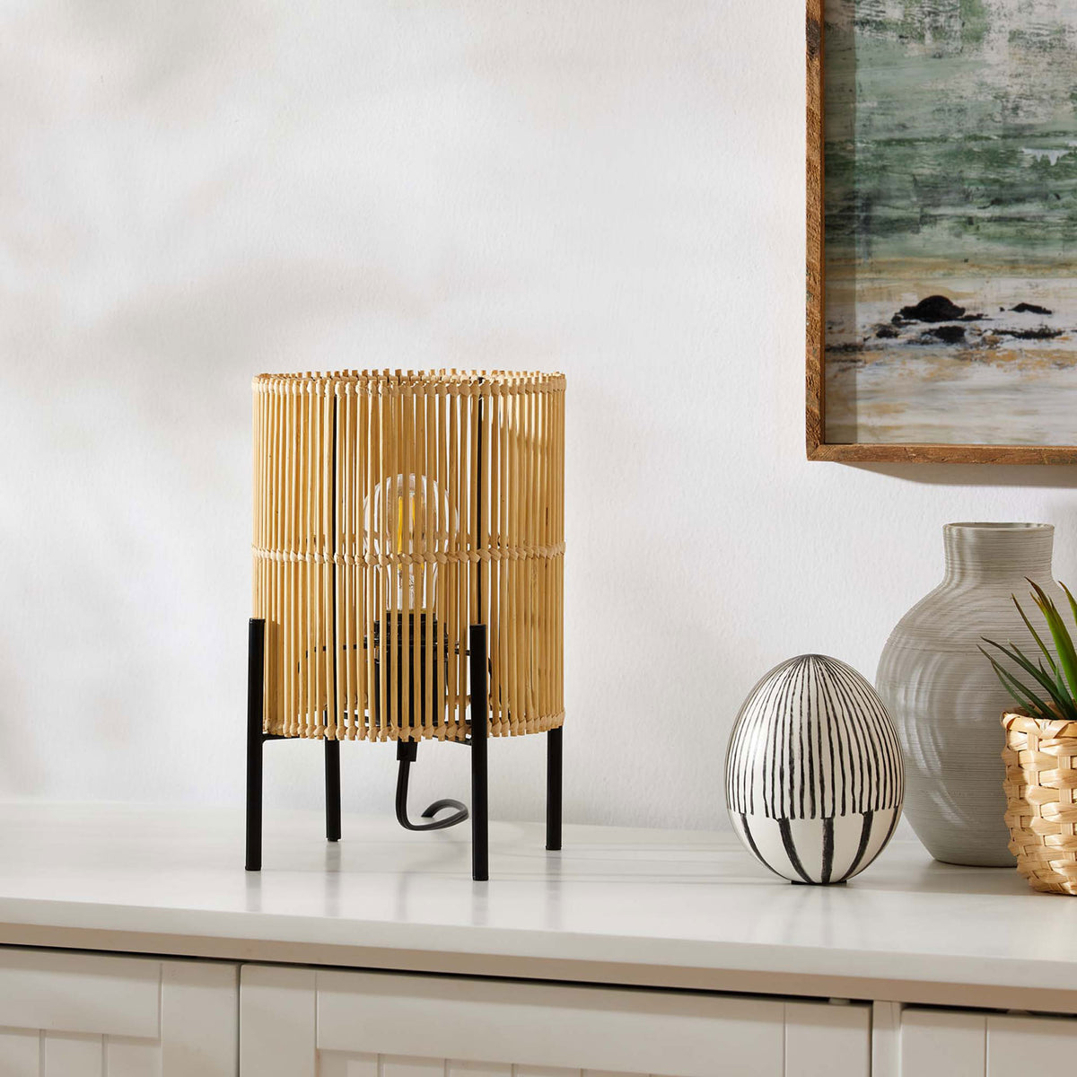 Casen bamboo table lamp styled on a white cabinet bringing organic warmth to a modern living space || EEI-5610-NAT || front_angle_room
