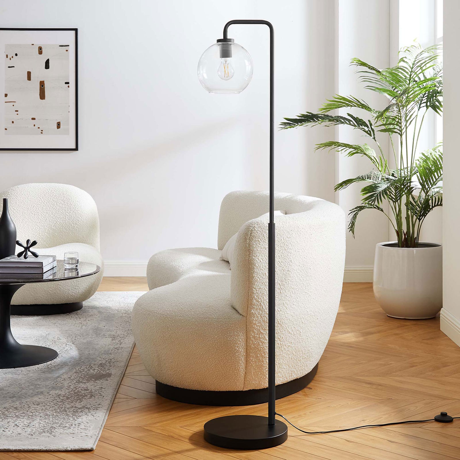 Silo black floor lamp with clear glass globe accenting a cozy contemporary living room with boucle chairs || EEI-5616-BLK || front_angle_room