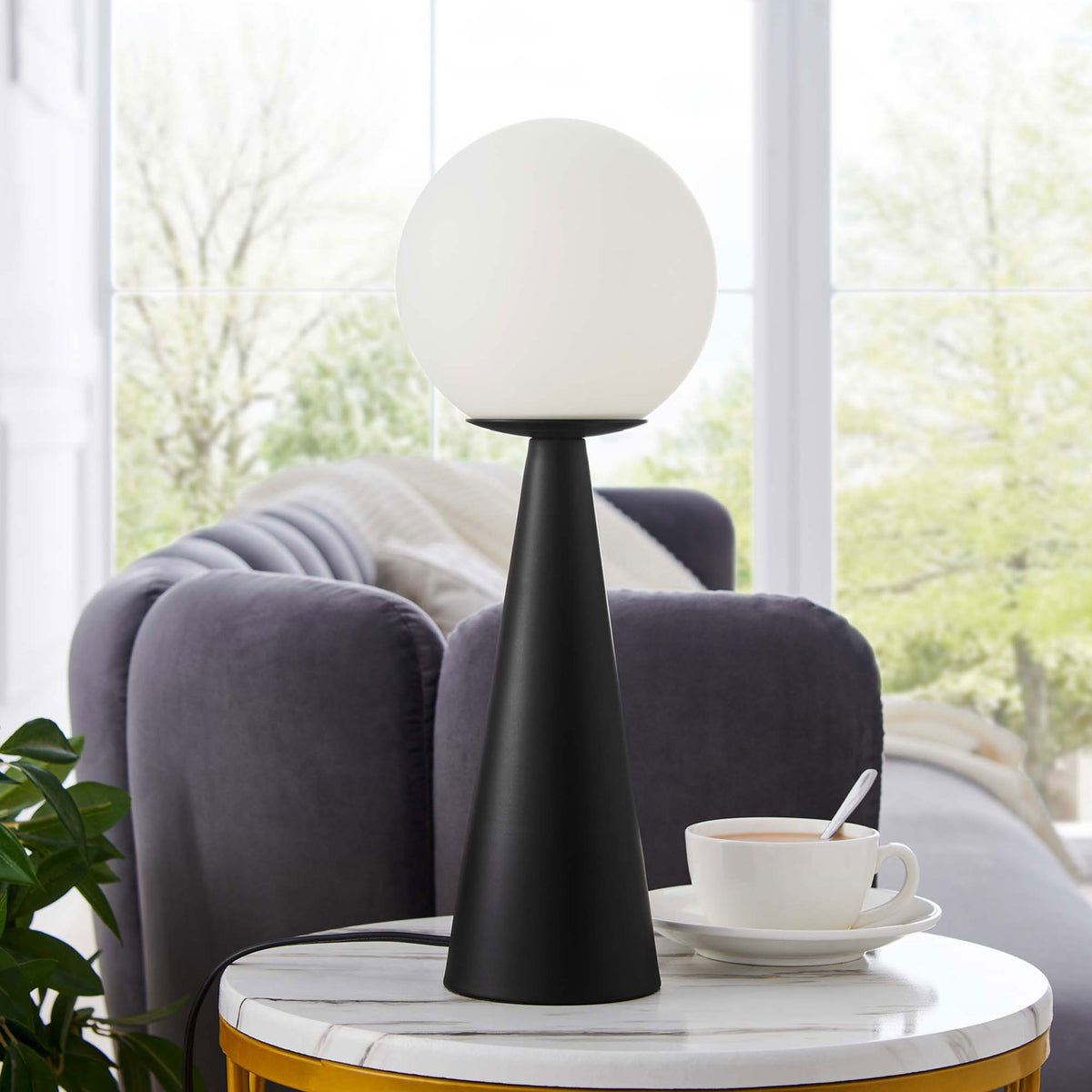 Apex glass globe lamp styled on a marble side table beside a plush sofa in bright living room || EEI-5621-WHI-BLK || front_angle_room