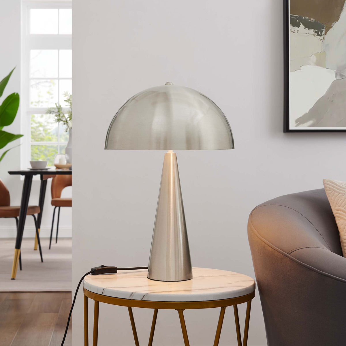 Selena satin nickel table lamp glowing on a marble side table to warm a contemporary living room || EEI-5624-SNL || front_on_room