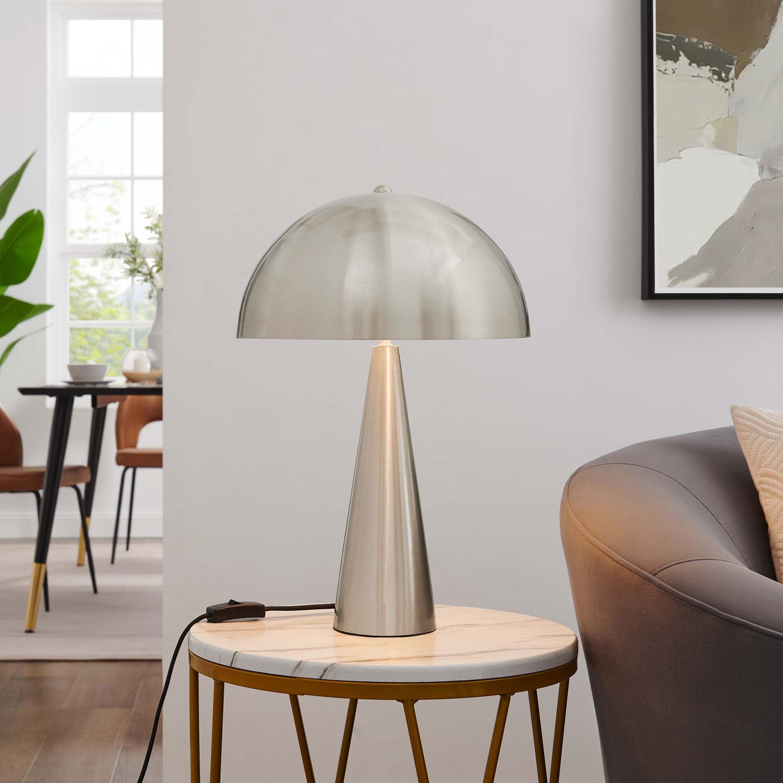 Selena satin nickel table lamp glowing on a marble side table to warm a contemporary living room || EEI-5624-SNL || front_on_room
