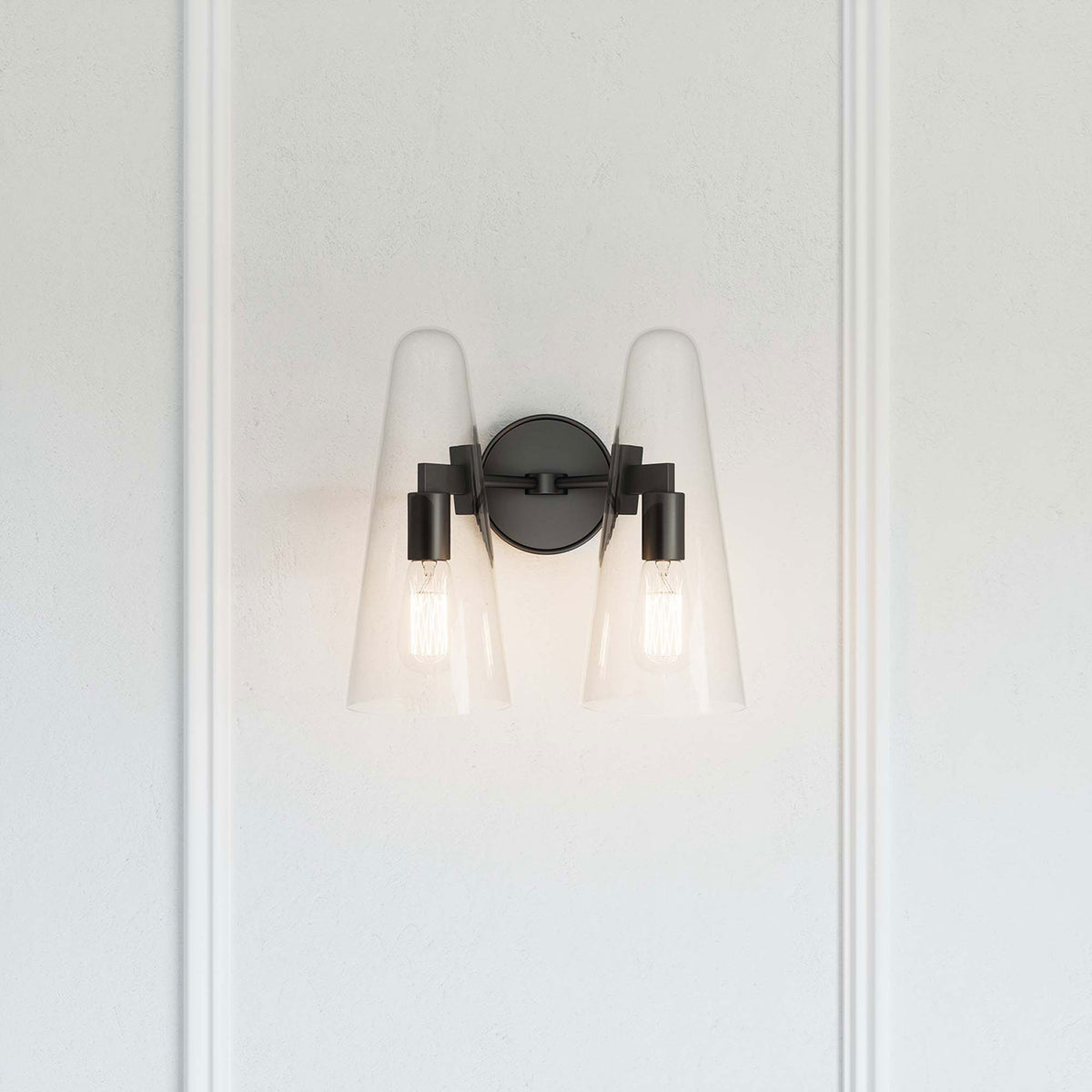 Beacon black 2-light wall sconce casting a warm glow against a paneled white wall || EEI-5646-CLR-BLK || front_on_room