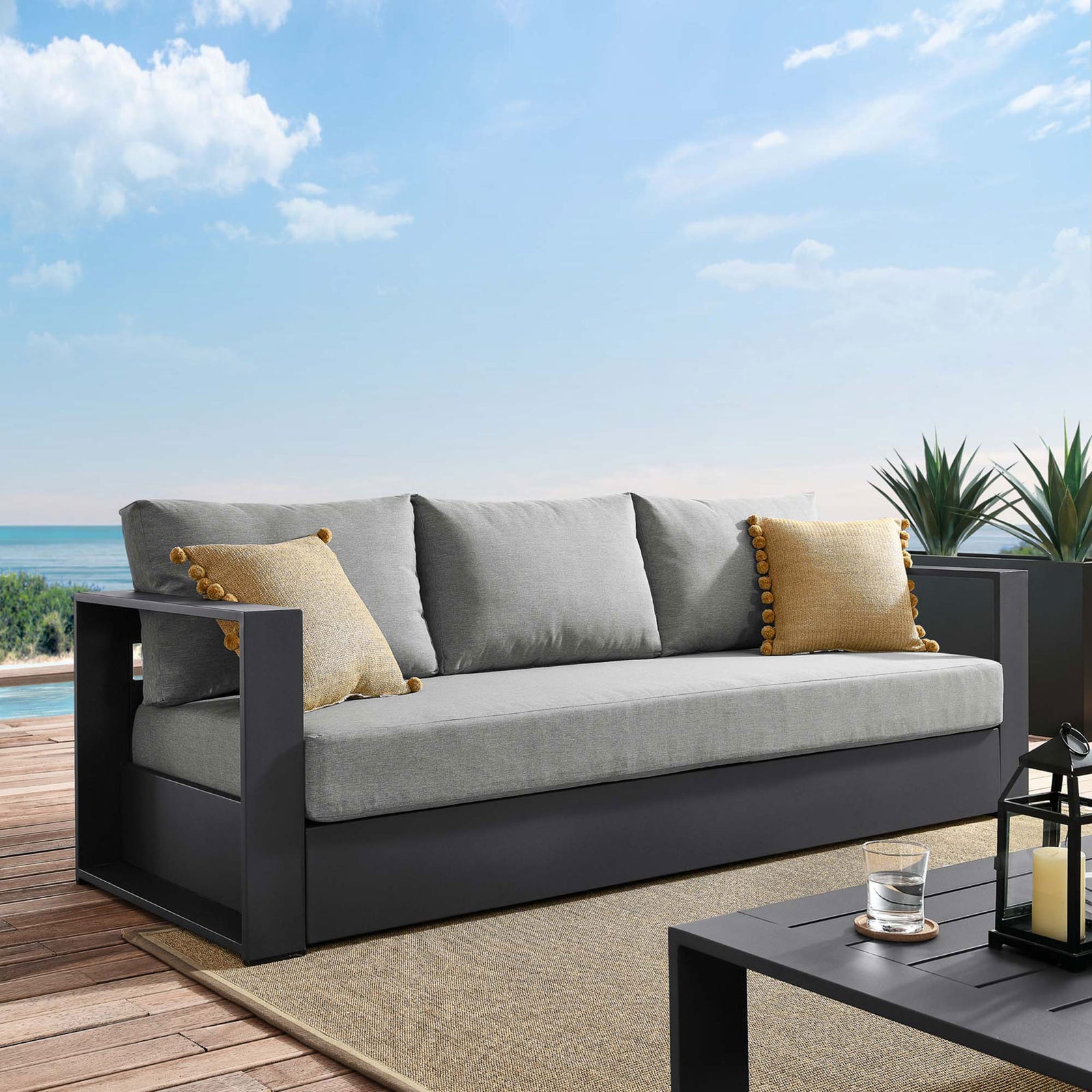 Tahoe outdoor sofa with light gray cushions styled on a deck with accent pillows and lantern. || EEI-5676-GRY-GRY || front_angle_room