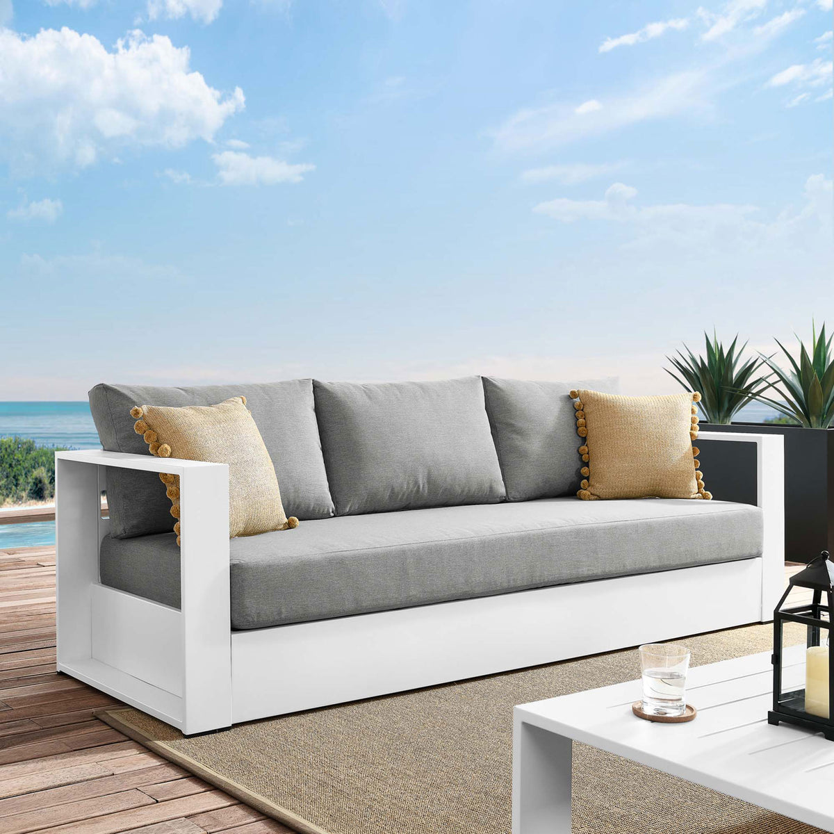 Tahoe outdoor sofa with white frame and gray cushions styled on a sunny deck with pillows. || EEI-5676-WHI-GRY || front_angle_room