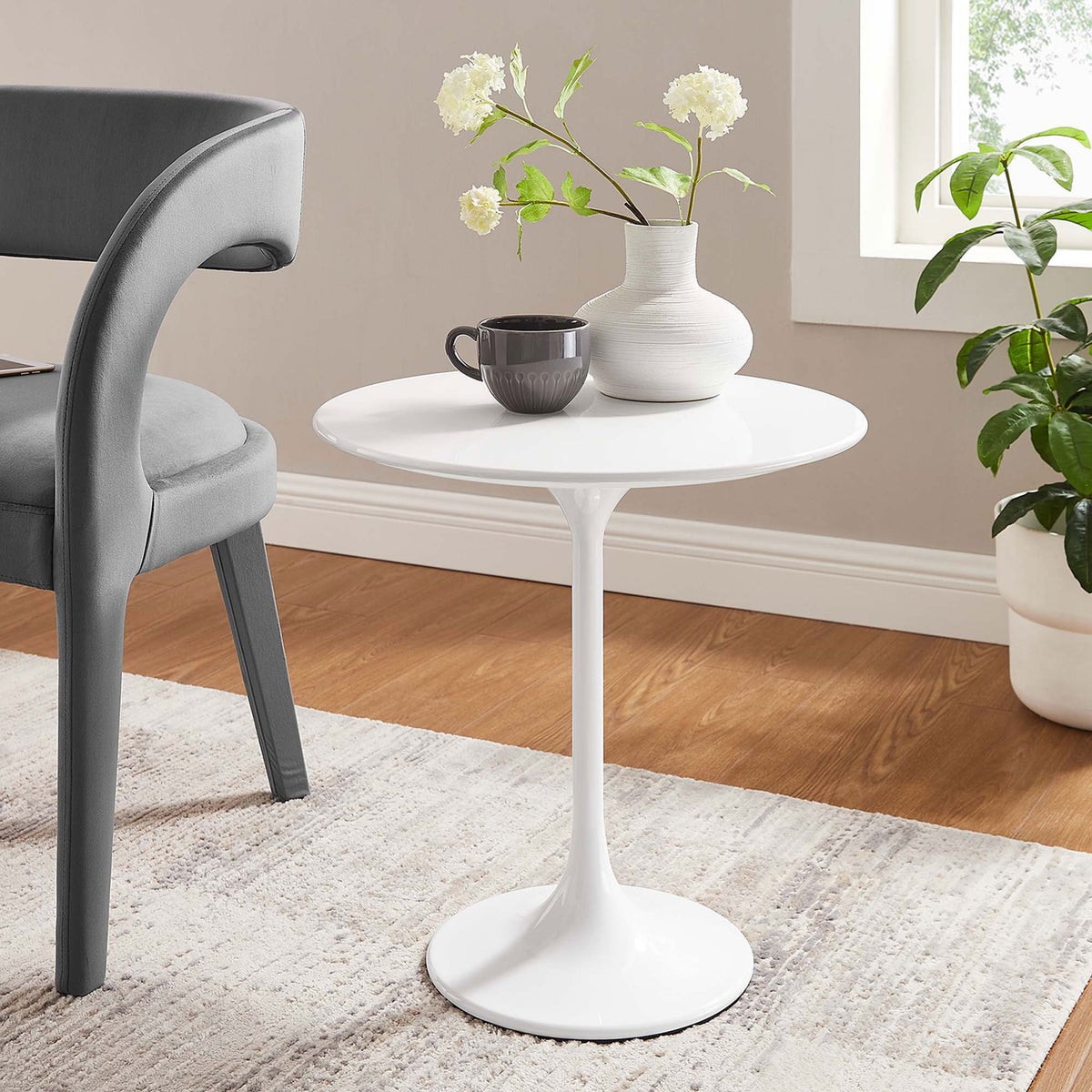 White Lippa pedestal side table styled beside a chair, perfect for drinks, decor, and everyday essentials || EEI-5678-WHI-WHI || front_angle_room